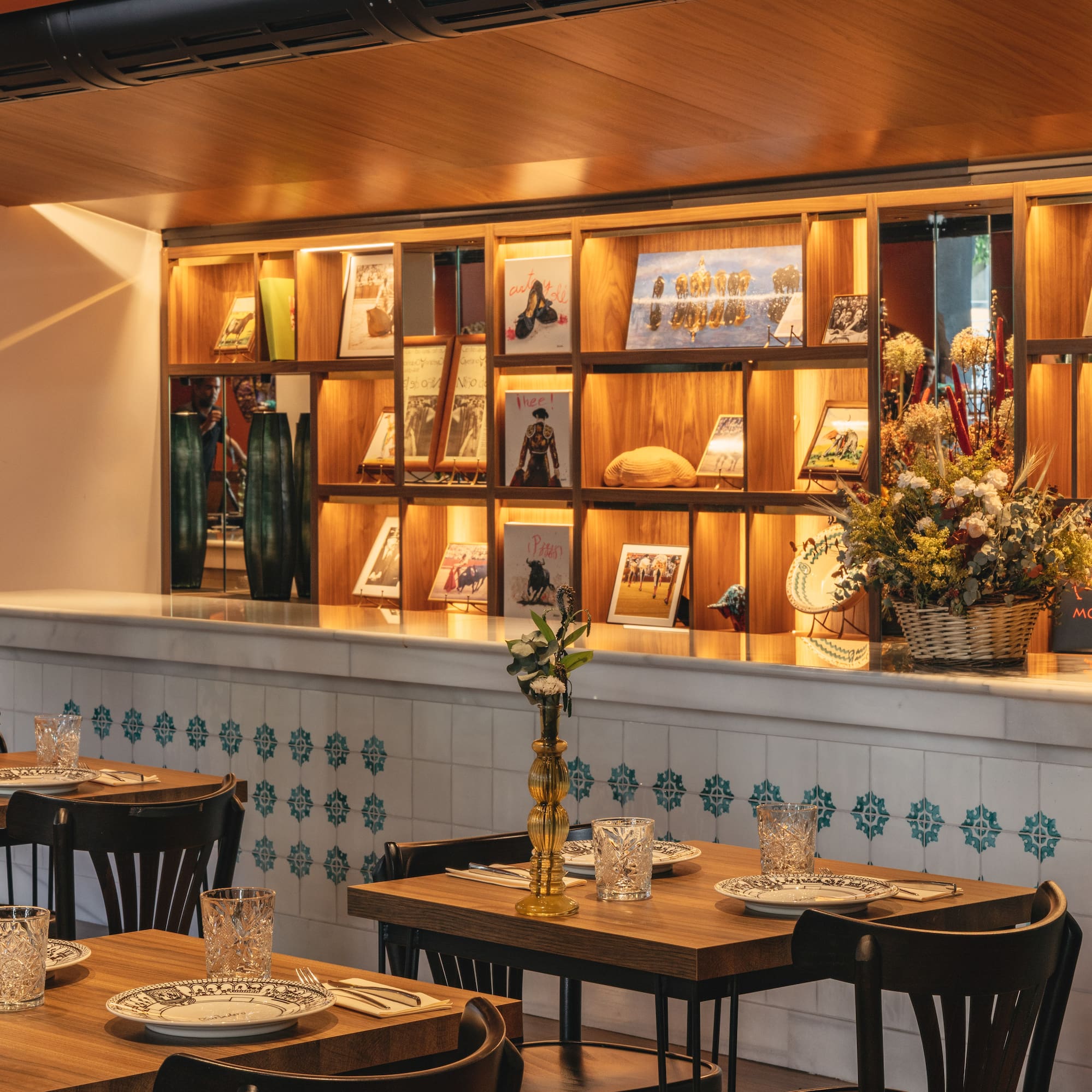 Comedor de restaurante con estantería decorada, mesas puestas y azulejos españoles.