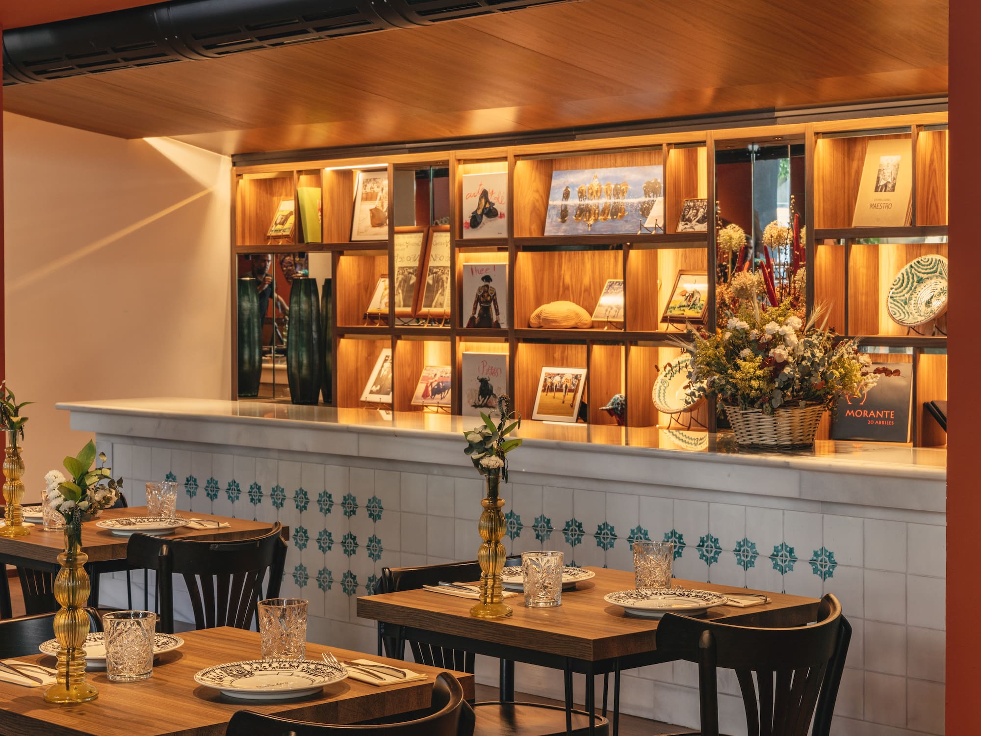 Comedor de restaurante con estantería decorada, mesas puestas y azulejos españoles.