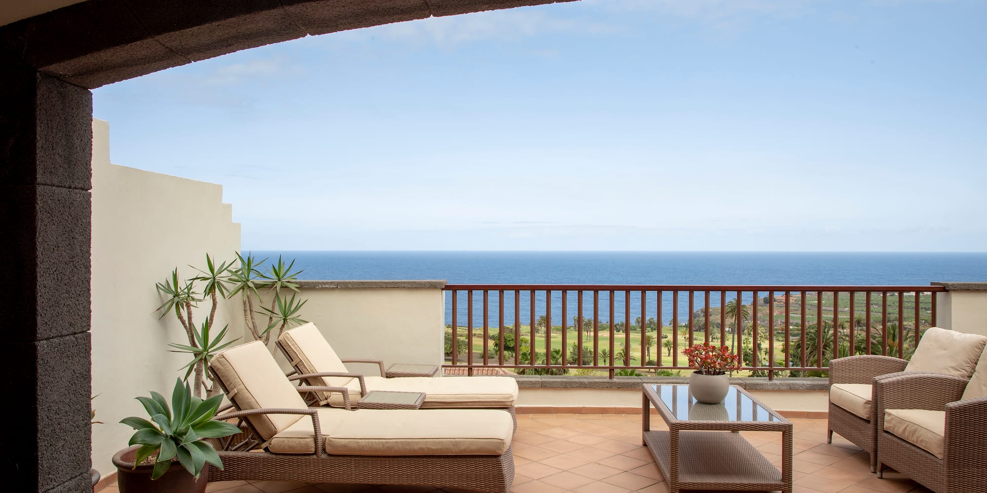 a deck with chairs and a table overlooking the ocean