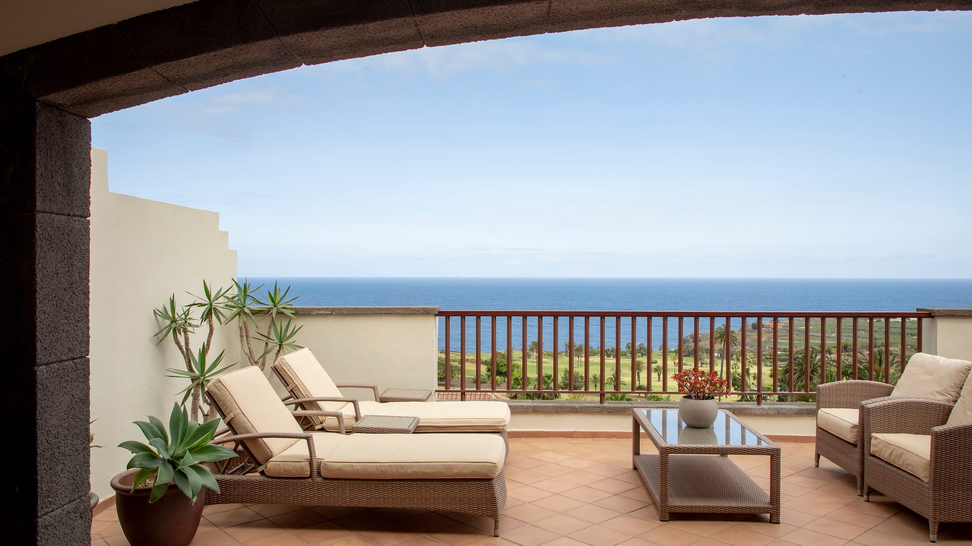 a deck with chairs and a table overlooking the ocean