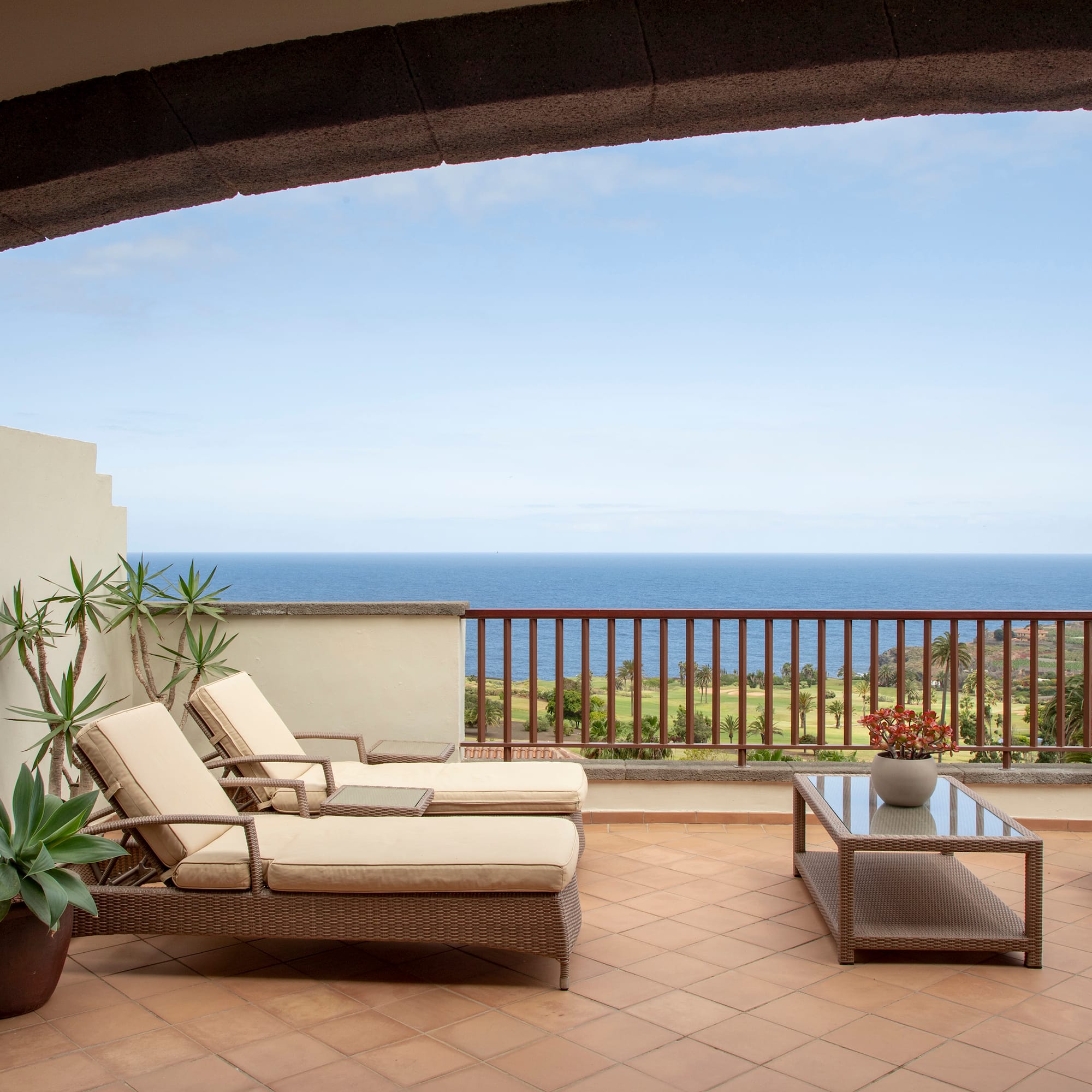 a deck with chairs and a table overlooking the ocean