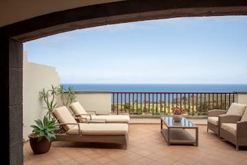 a deck with chairs and a table overlooking the ocean