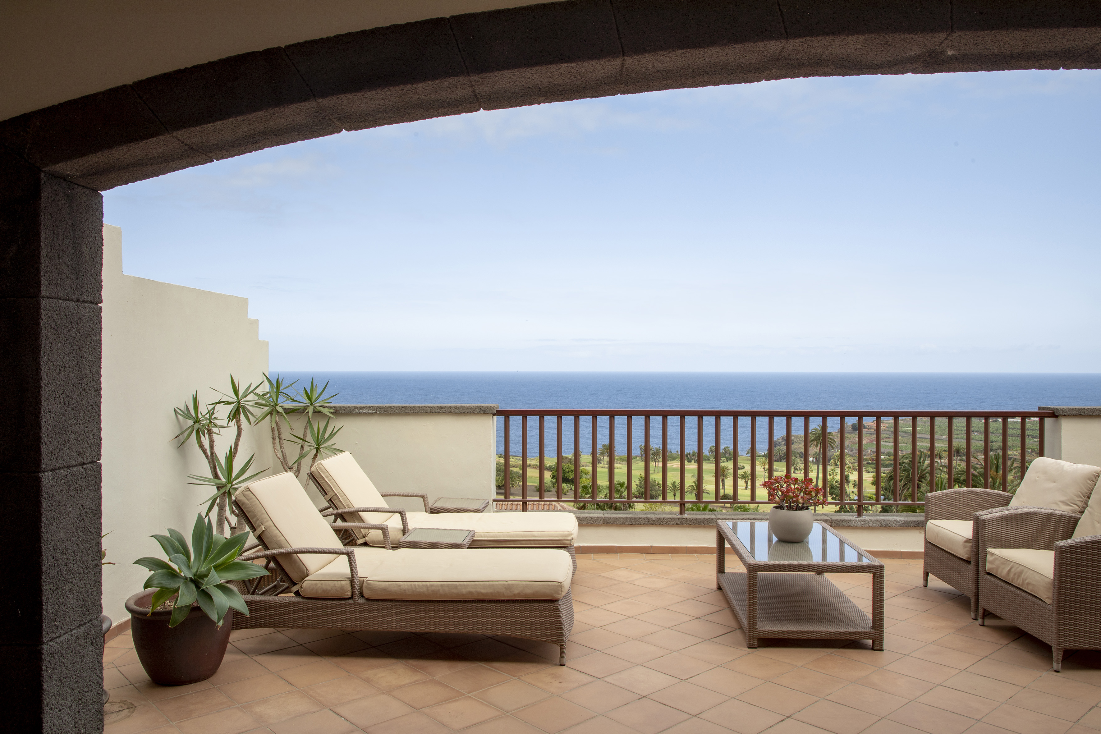 Ocean view terrace with rattan lounge chairs, patio furniture, and golf course.