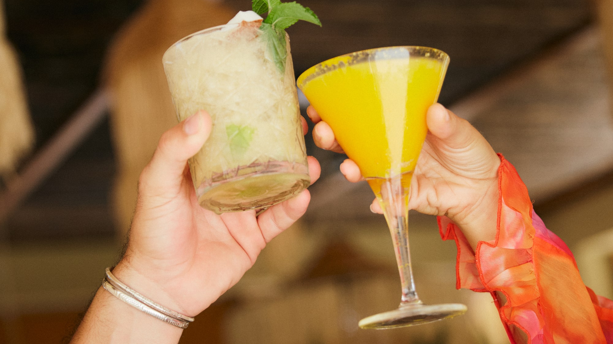 a pair of hands holding up a glass of drinks