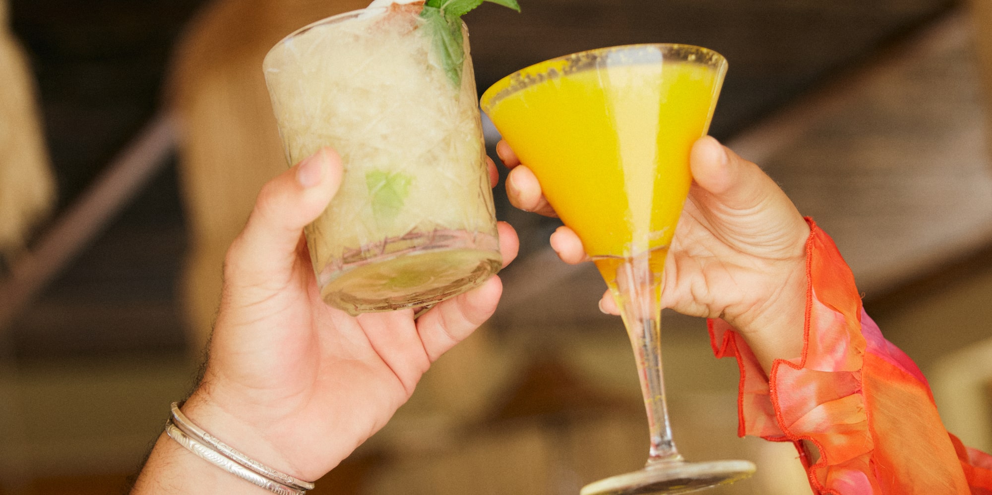 a pair of hands holding up a glass of drinks