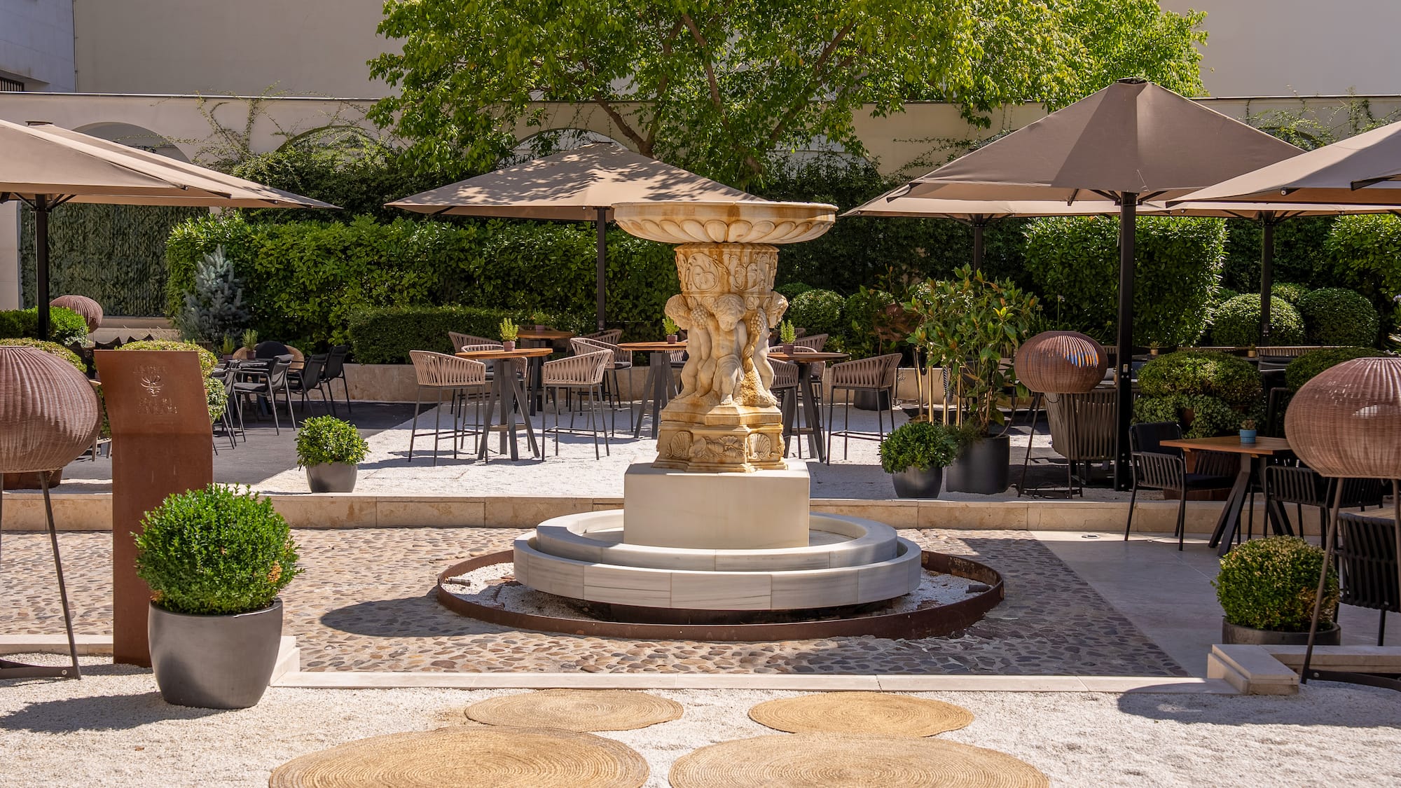 a fountain with a group of chairs and umbrellas