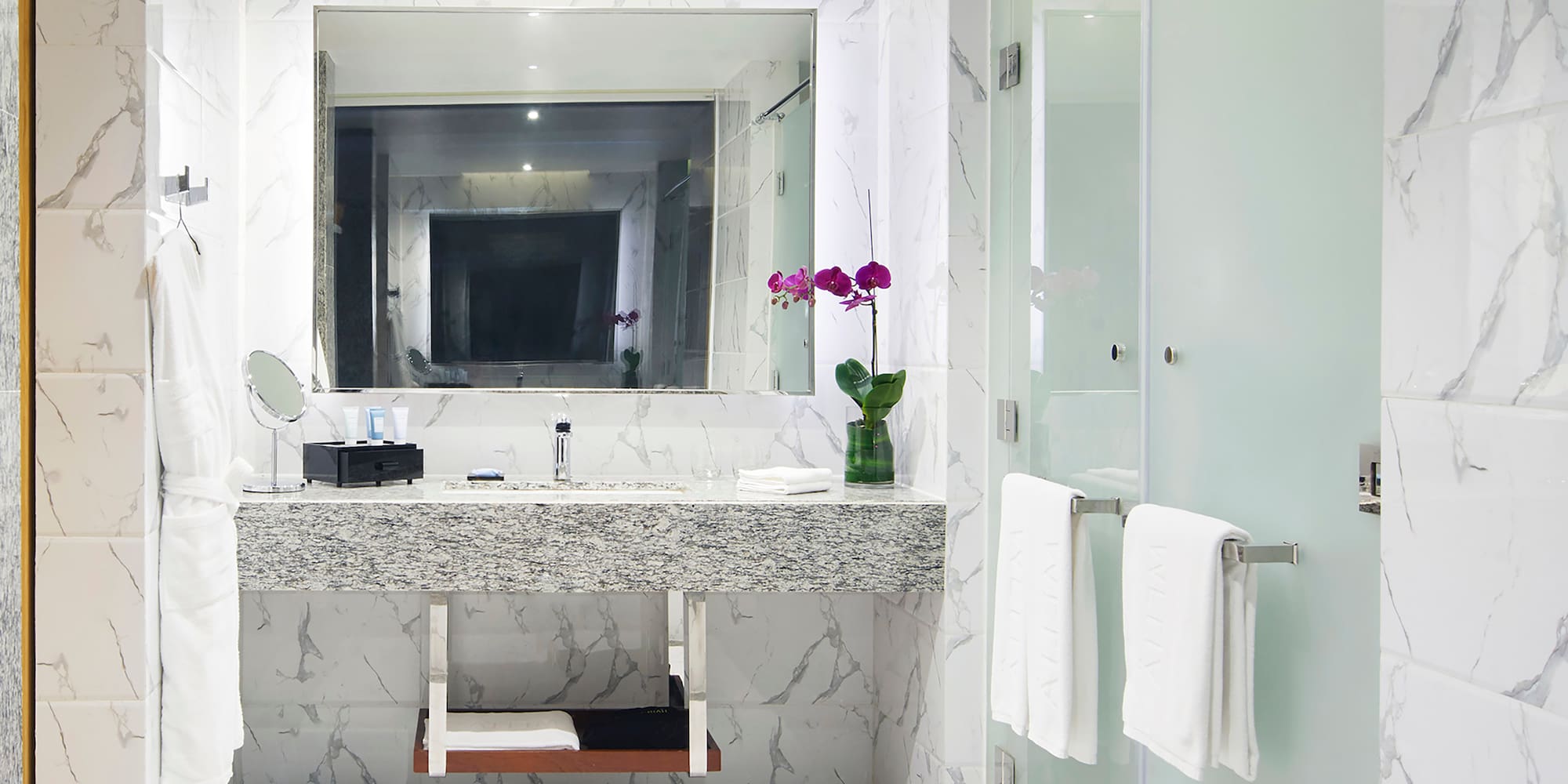 a bathroom with a marble countertop sink and a glass shower door