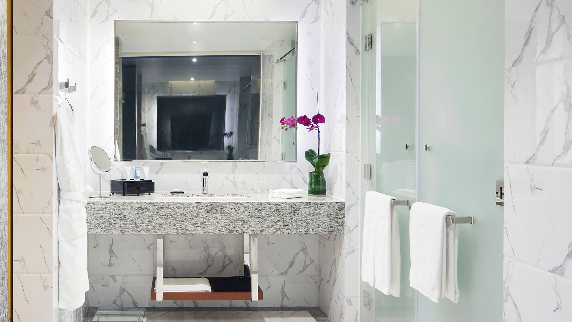 a bathroom with a marble countertop sink and a glass shower door