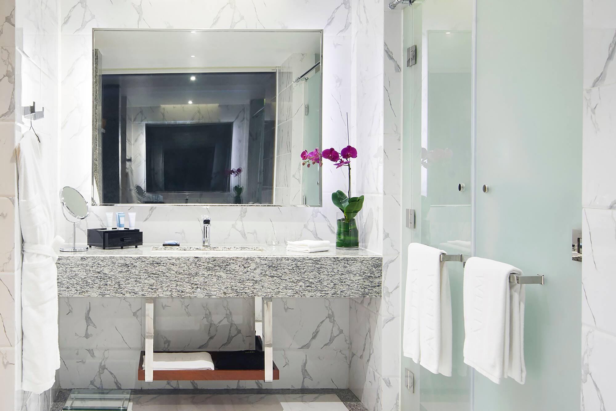 a bathroom with a marble countertop sink and a glass shower door