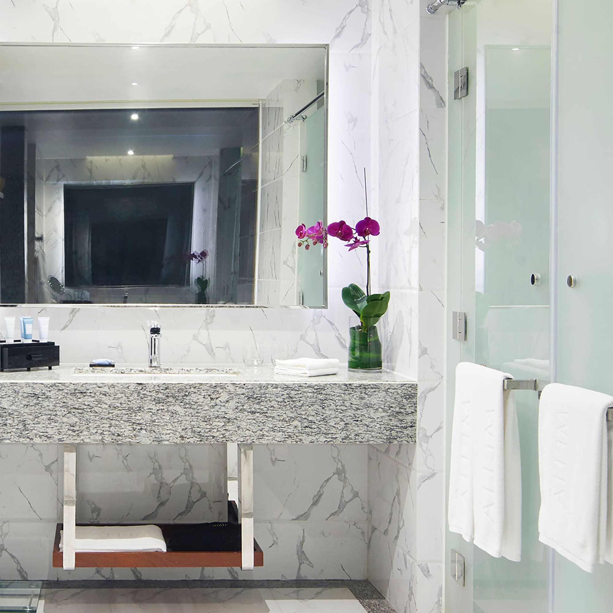 a bathroom with a marble countertop sink and a glass shower door