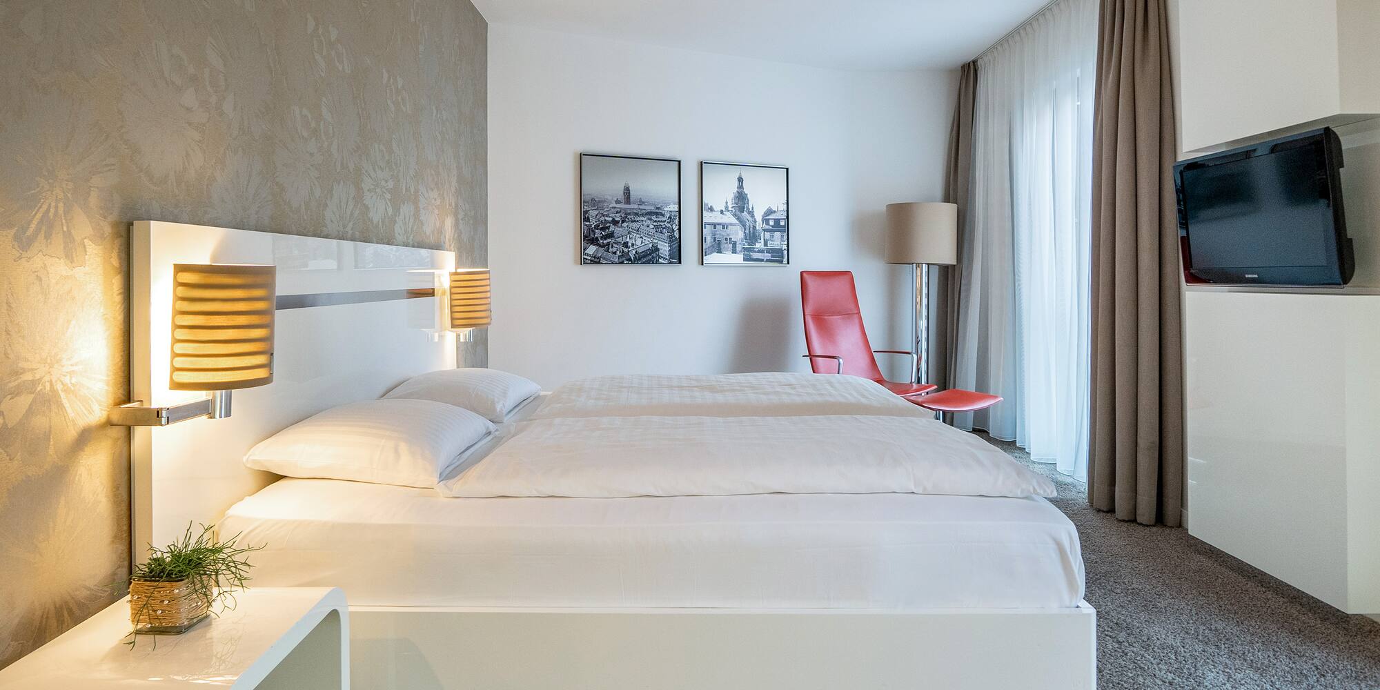 a bed with lamps and a red chair in a room