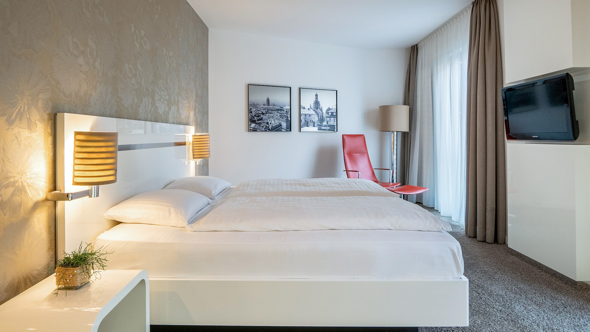 a bed with lamps and a red chair in a room