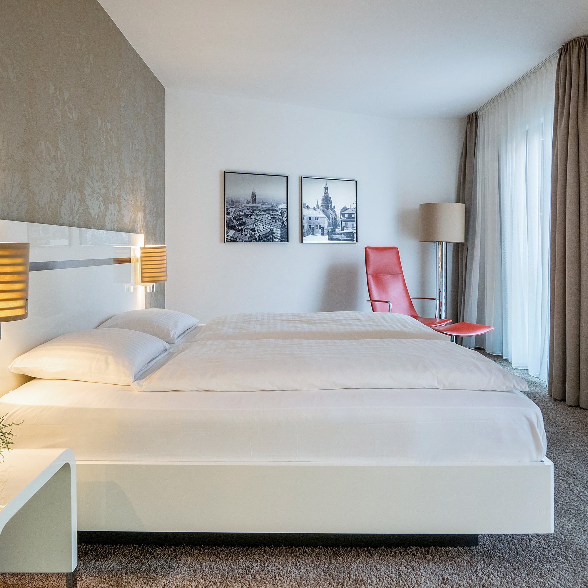 a bed with lamps and a red chair in a room