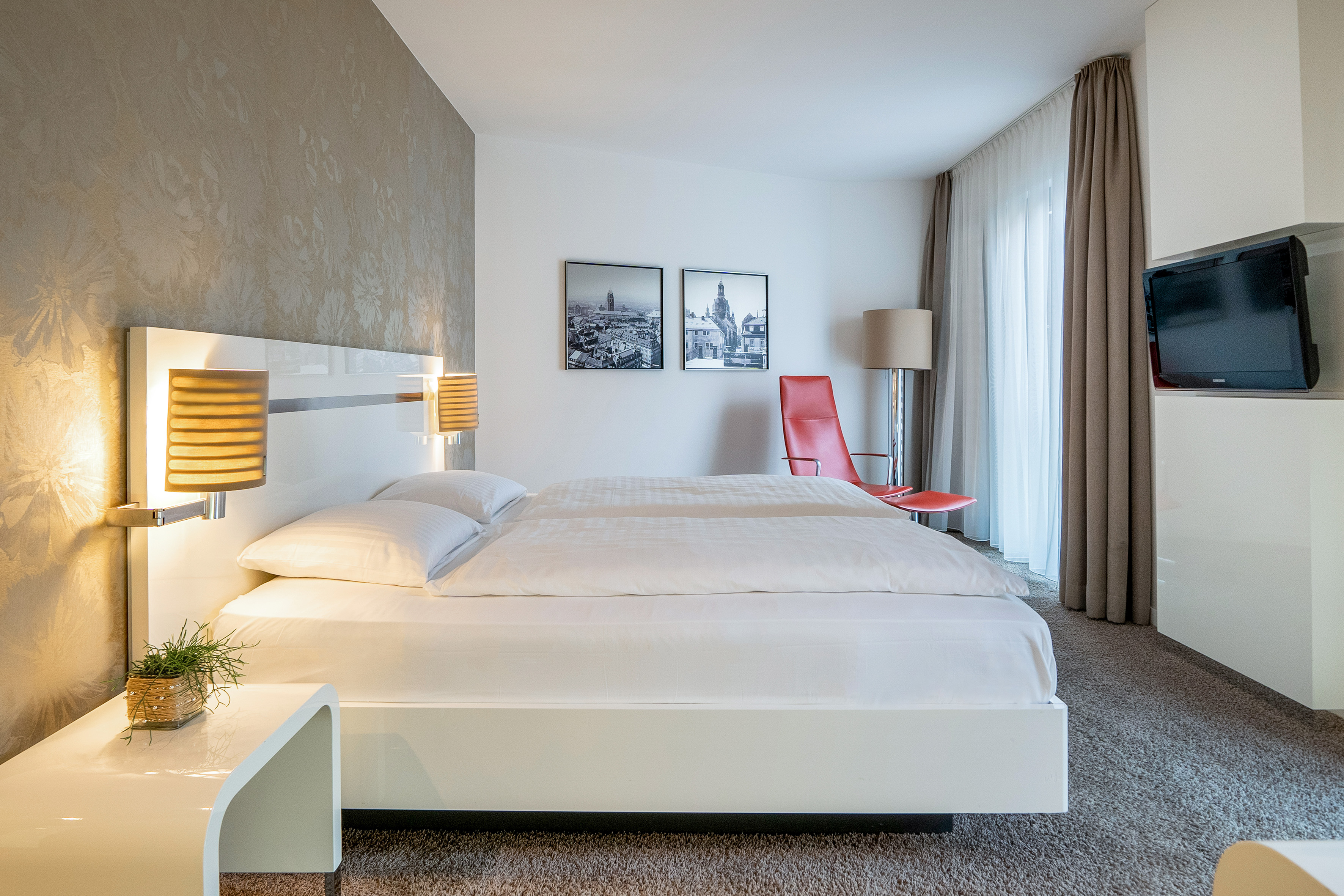 a bed with lamps and a red chair in a room