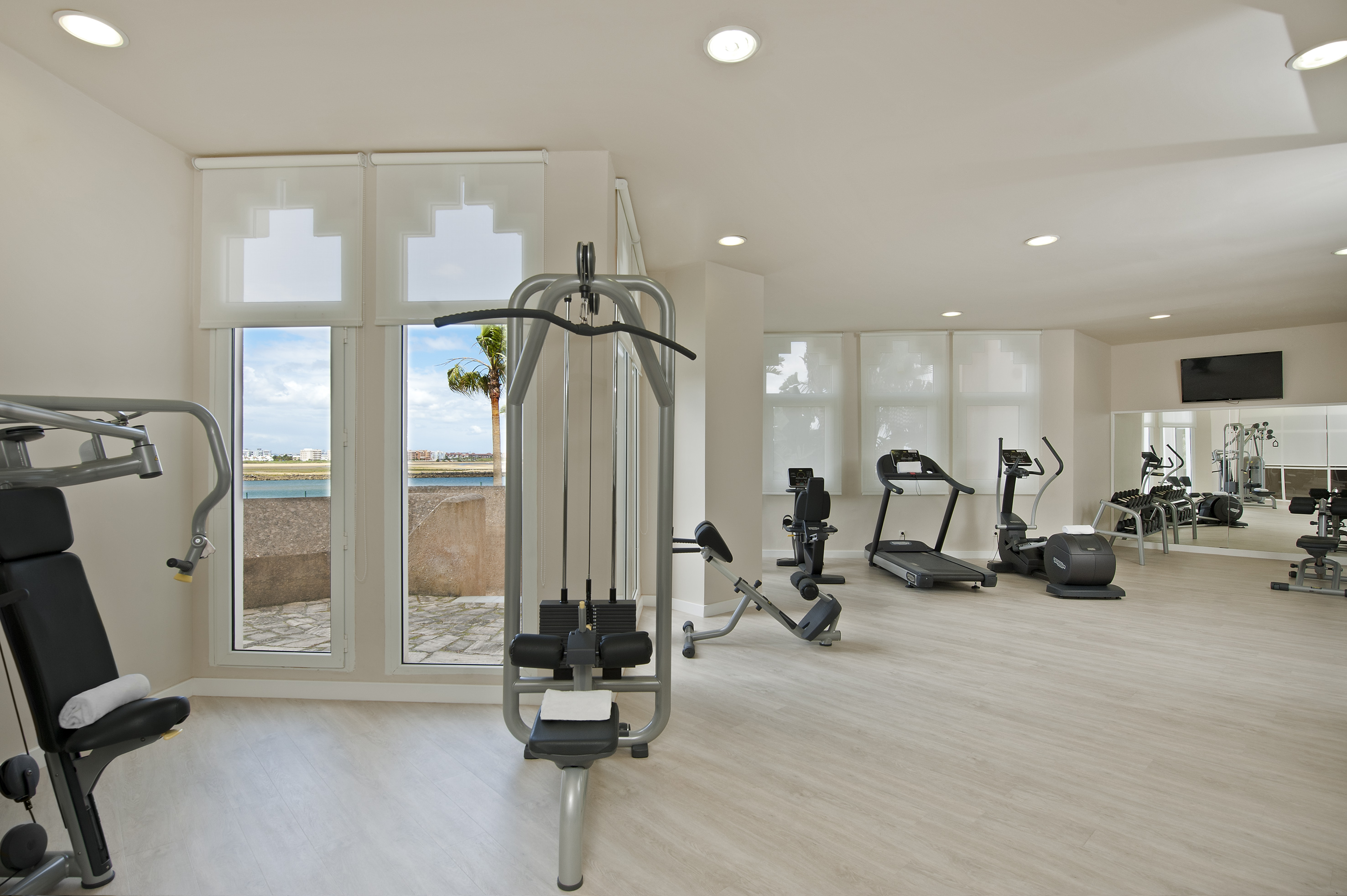 Modern gym with various workout equipment and scenic ocean view.