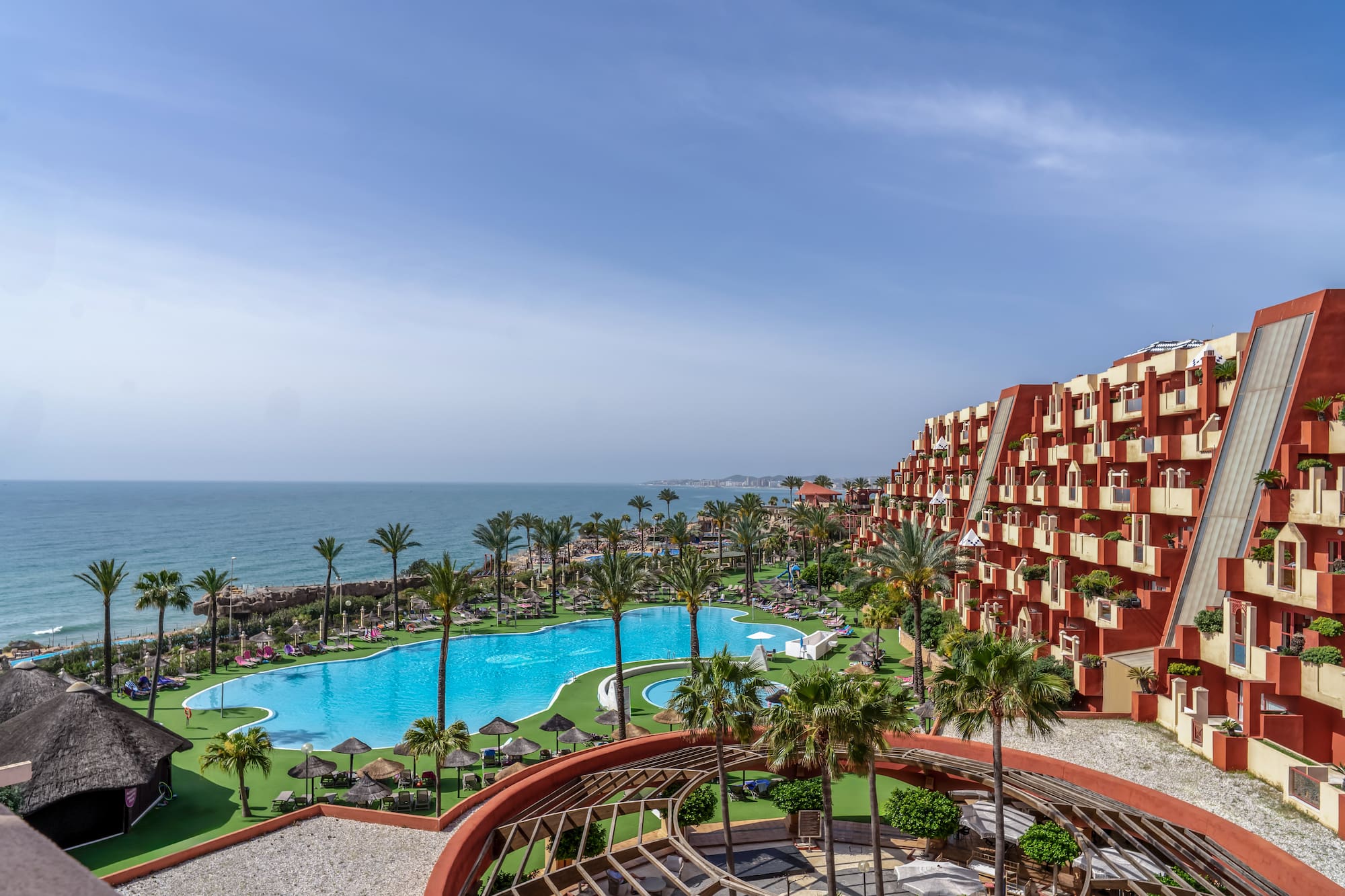 a pool and buildings with palm trees and a body of water