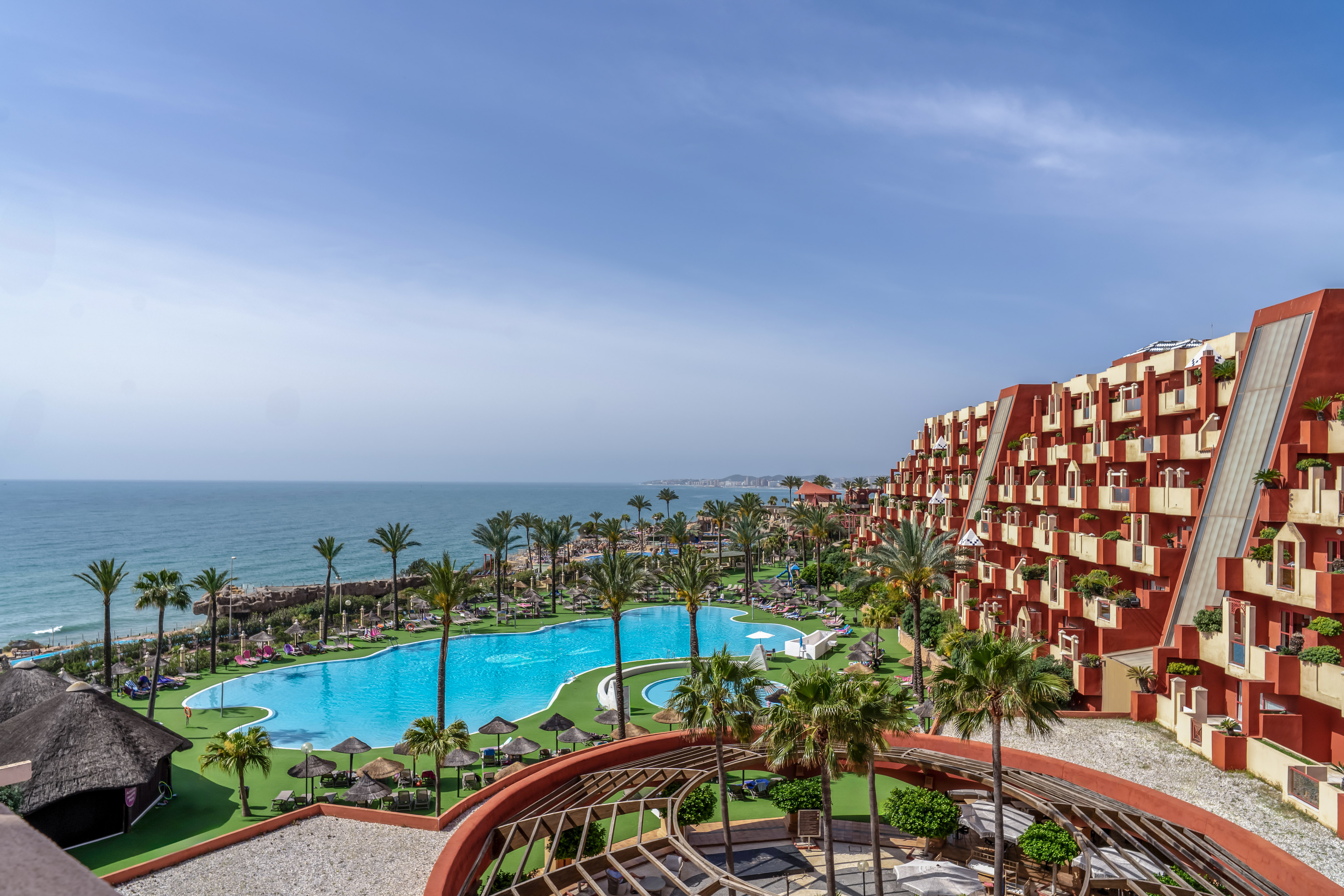 a pool and buildings with palm trees and a body of water