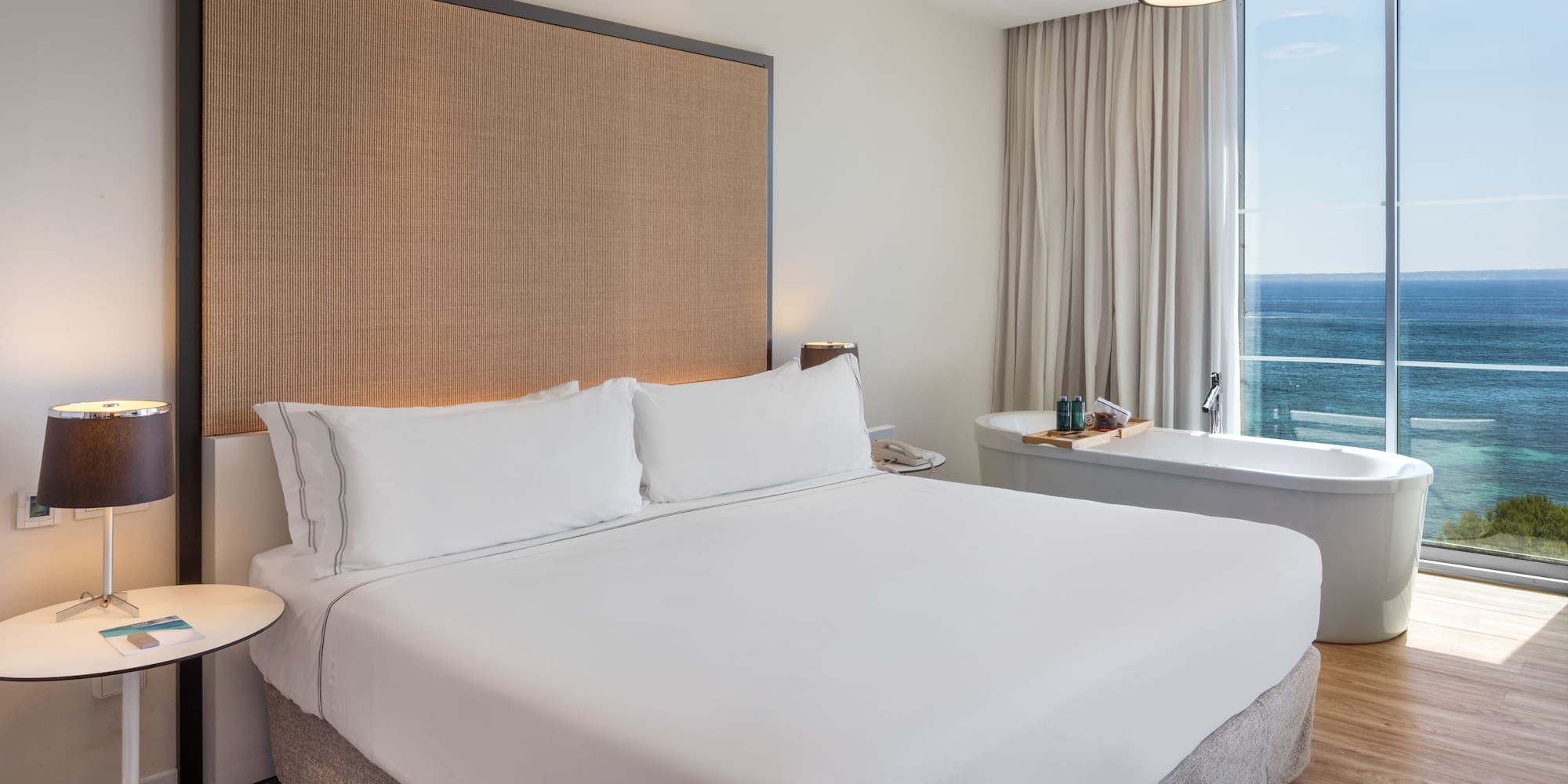 a bed with a large headboard and a bathtub in a hotel room