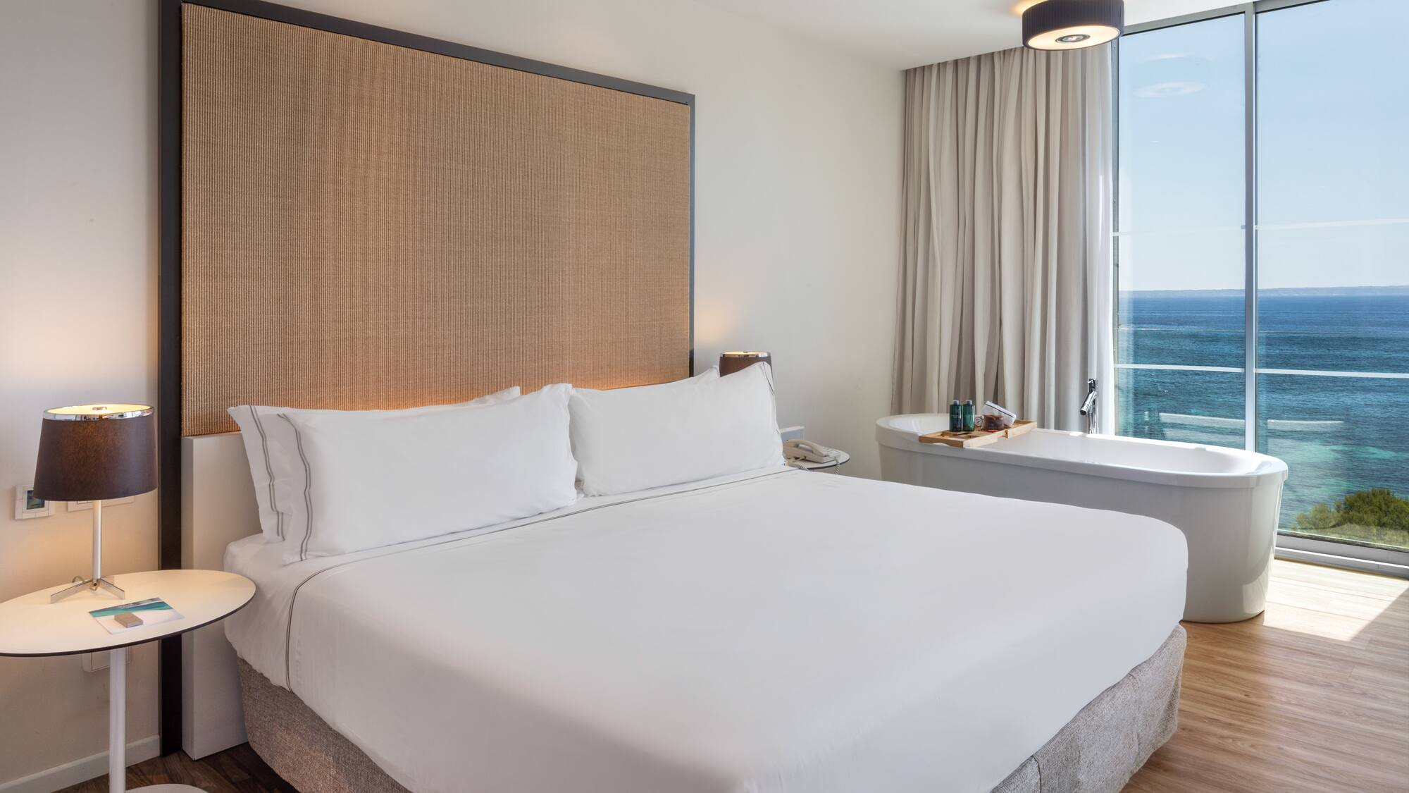 a bed with a large headboard and a bathtub in a hotel room