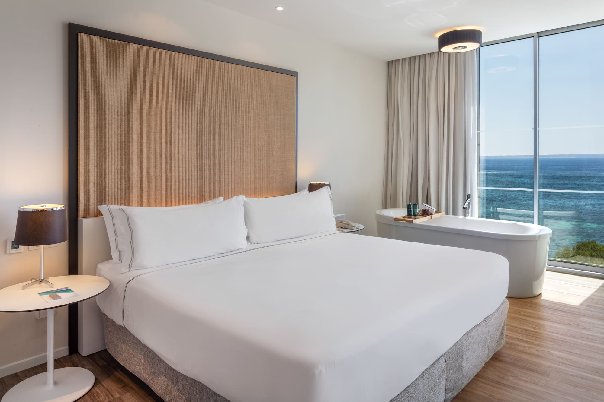 a bed with a large headboard and a bathtub in a hotel room