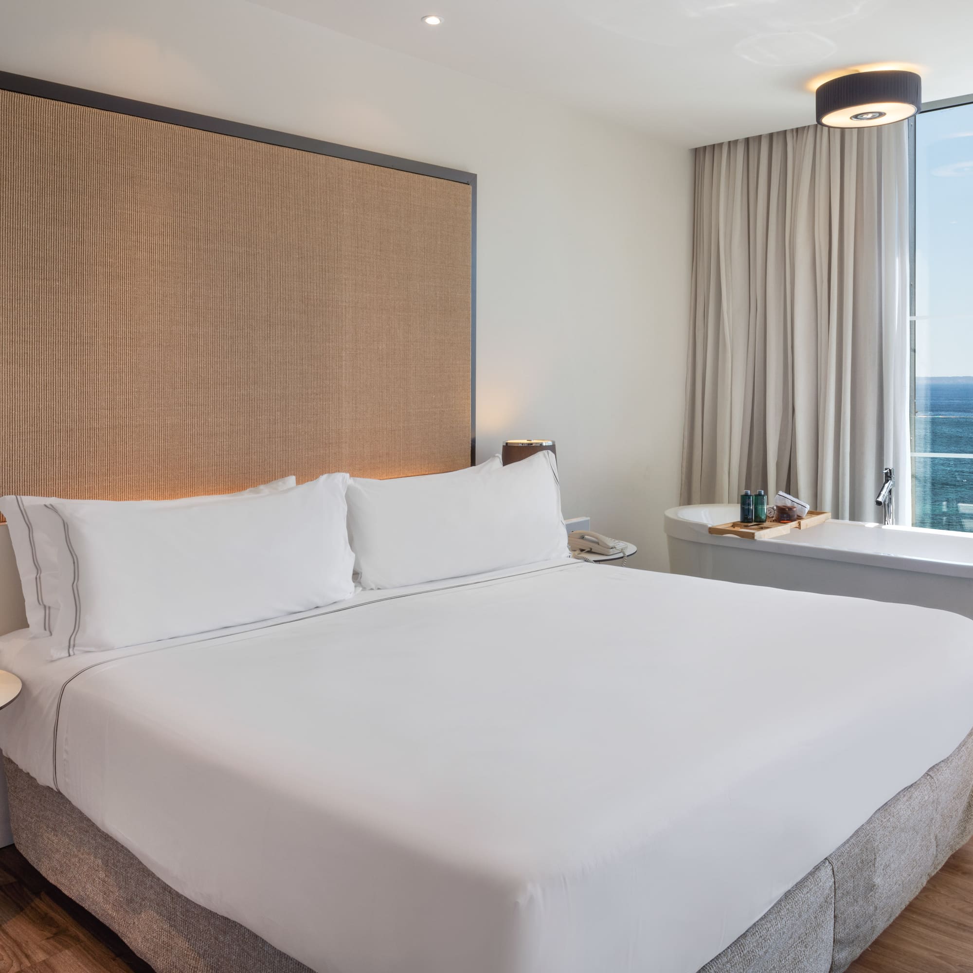 a bed with a large headboard and a bathtub in a hotel room