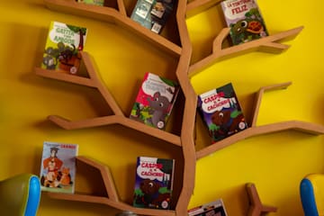 a girl sitting in front of a tree shaped shelf