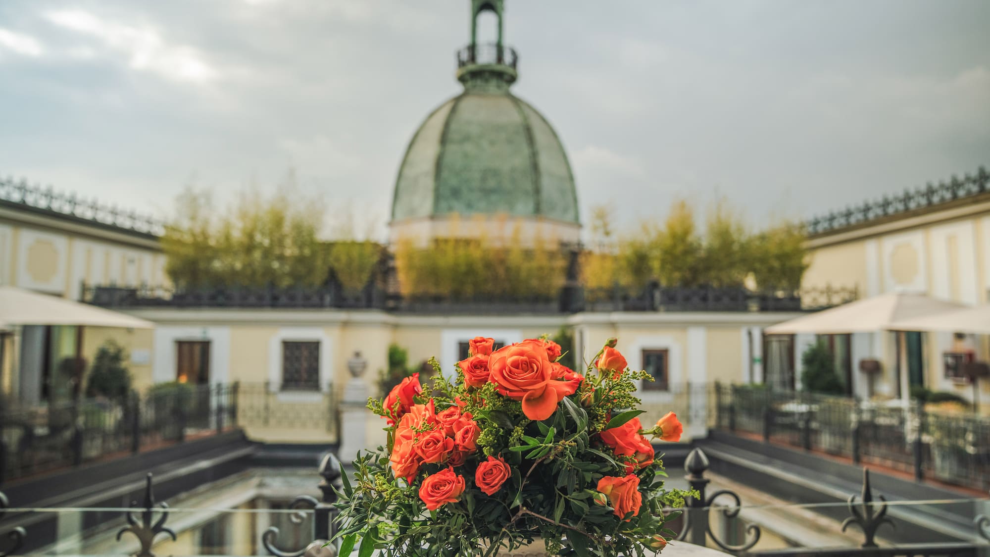 a bouquet of orange roses on a table with a dome in the background