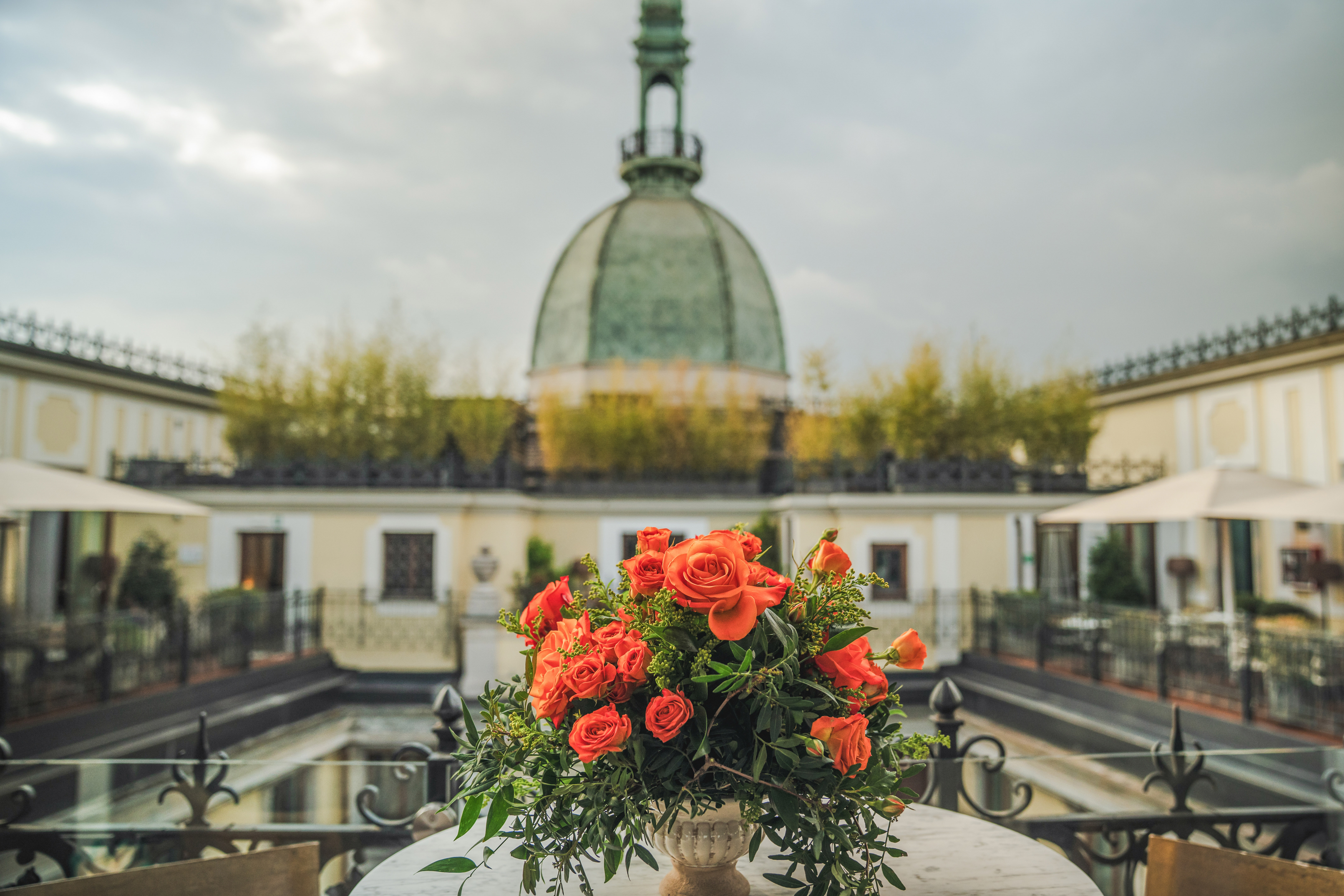 a bouquet of orange roses on a table with a dome in the background