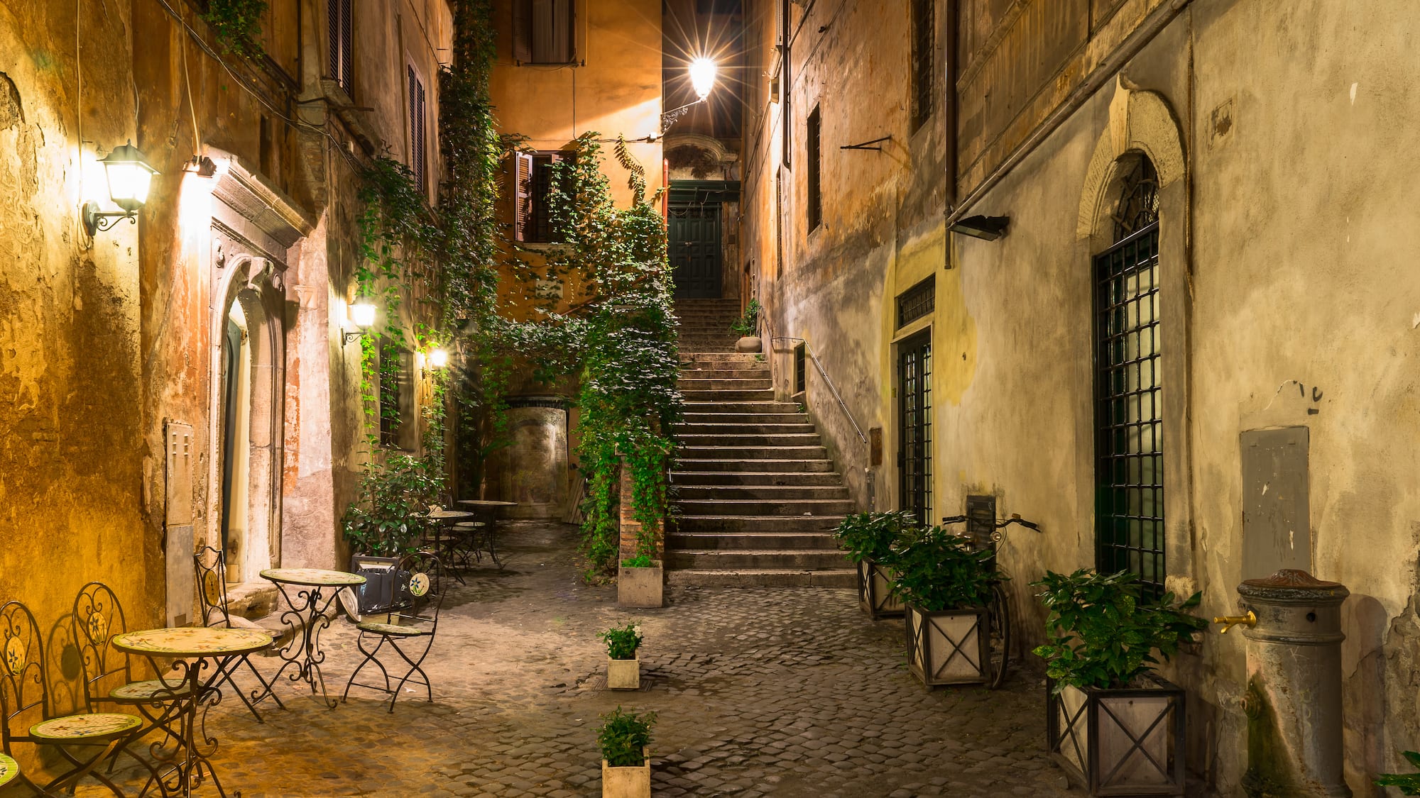 a courtyard with stairs and tables and plants