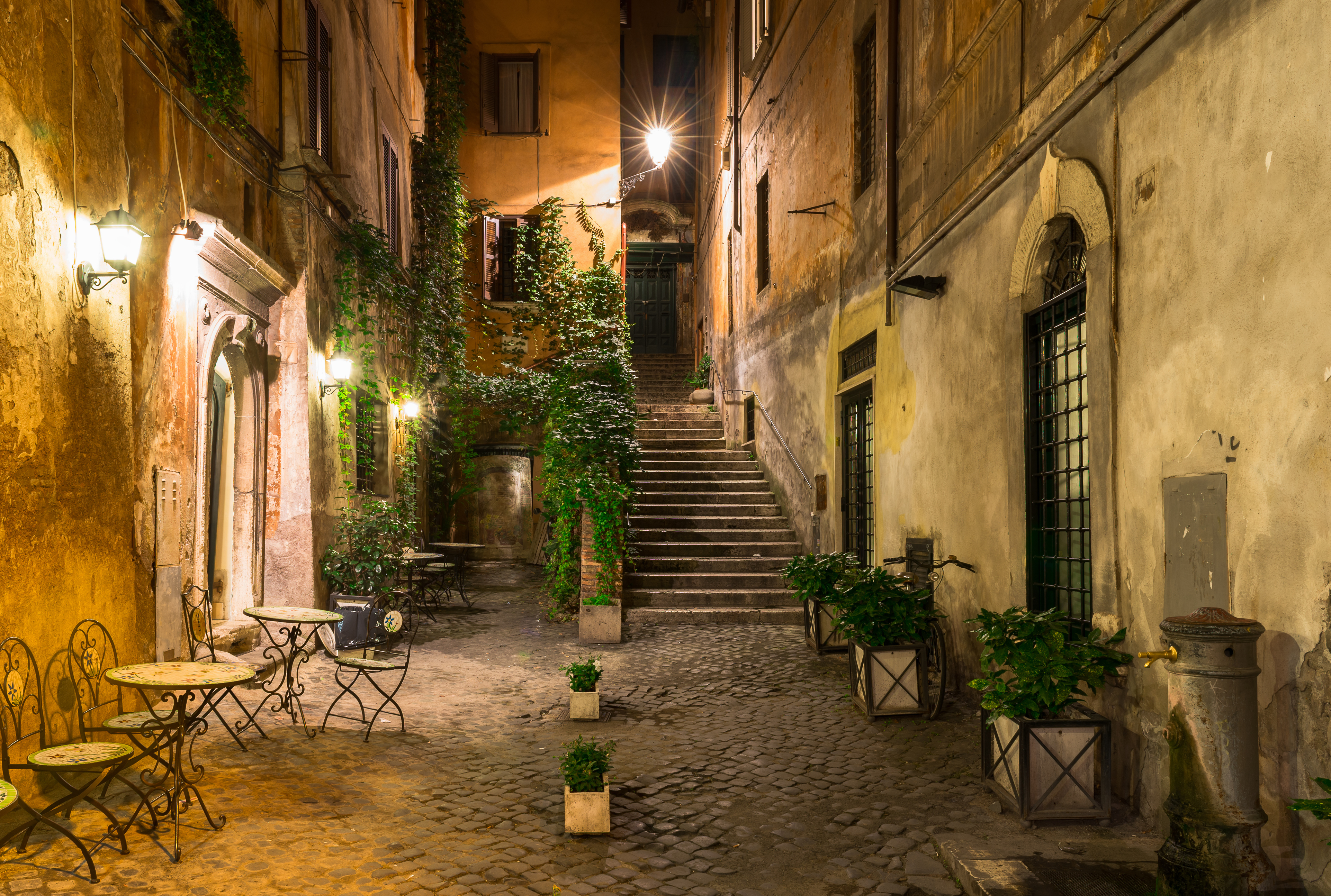 a courtyard with stairs and tables and plants