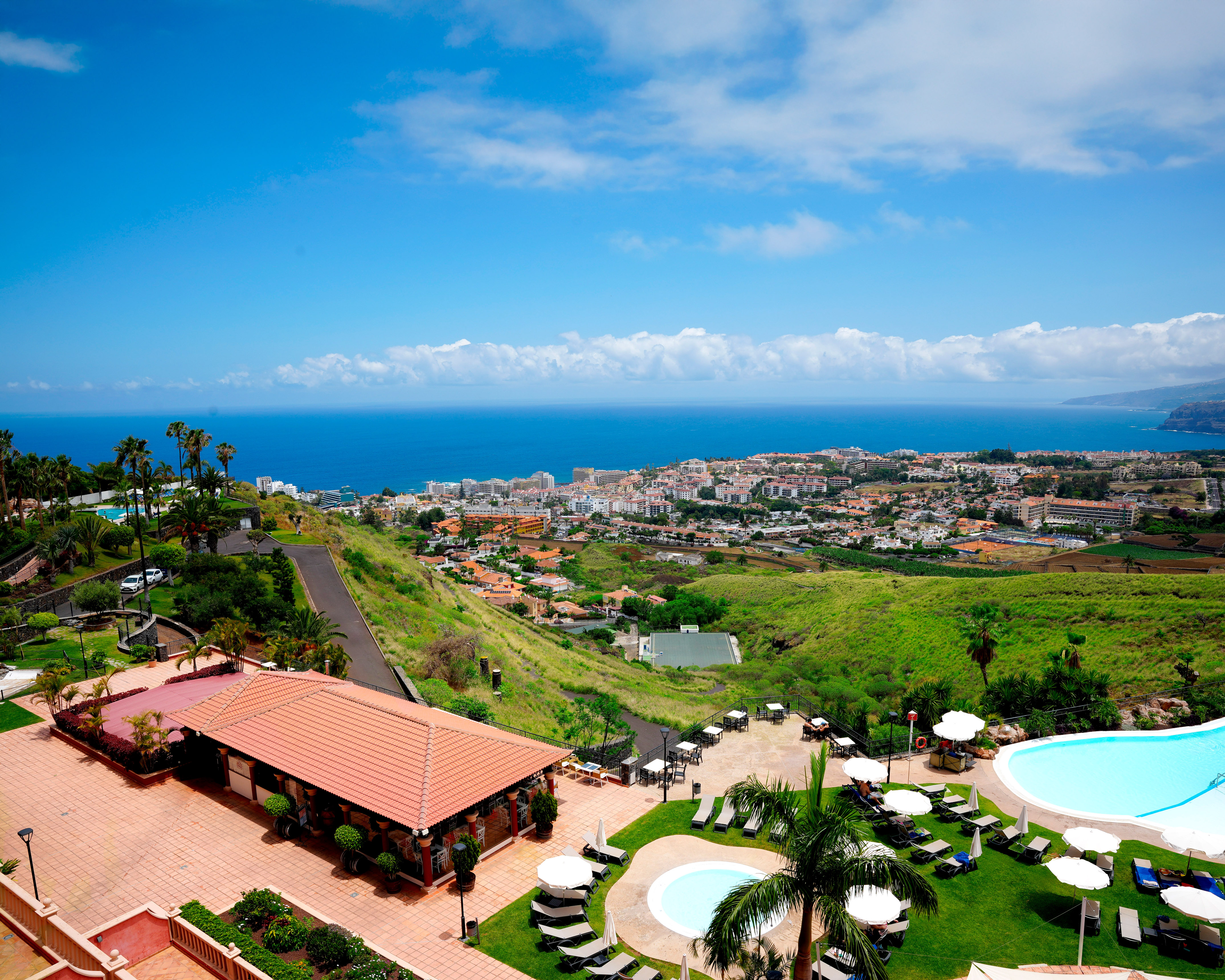 Coastal resort with swimming pools, palm trees, and ocean view town.