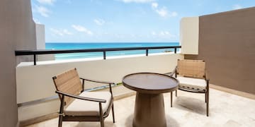 a table and chairs on a balcony overlooking the ocean