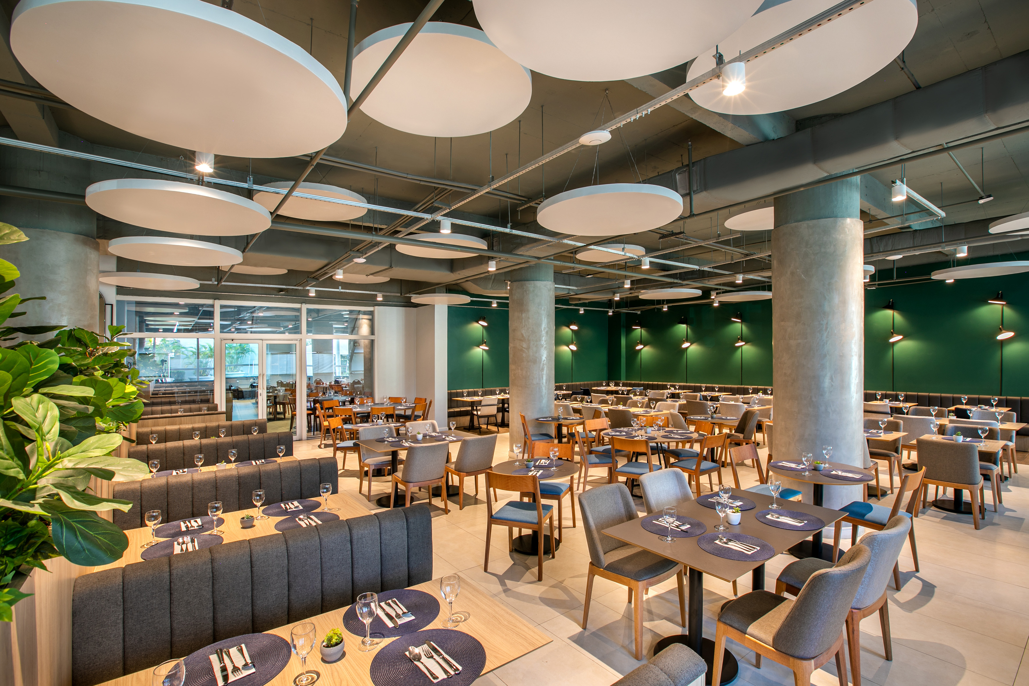 Modern restaurant dining interior with green accent wall, tables, and booths.