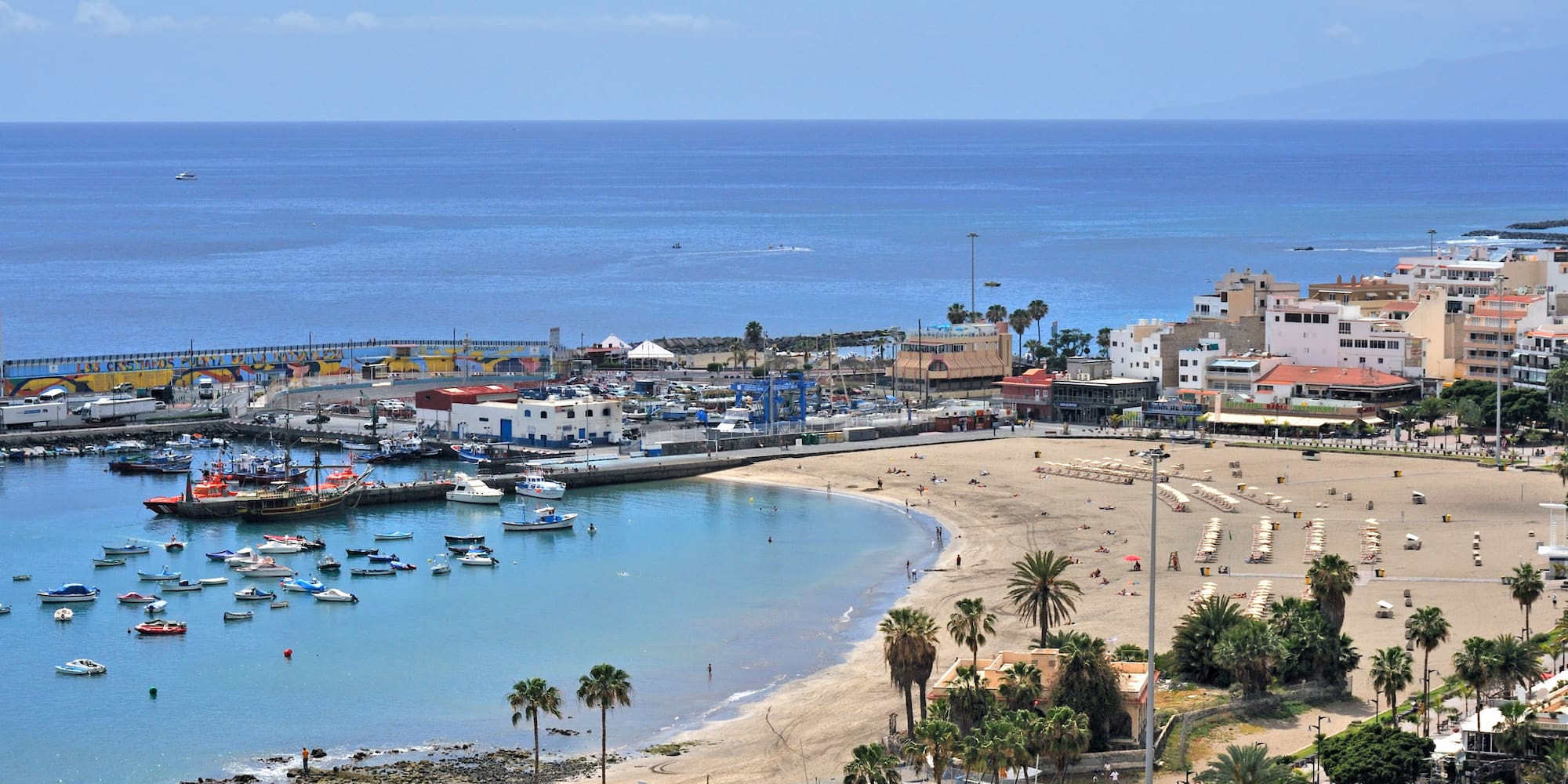 Aerial view of Los Cristianos Beach, harbor with boats, and coastal town.