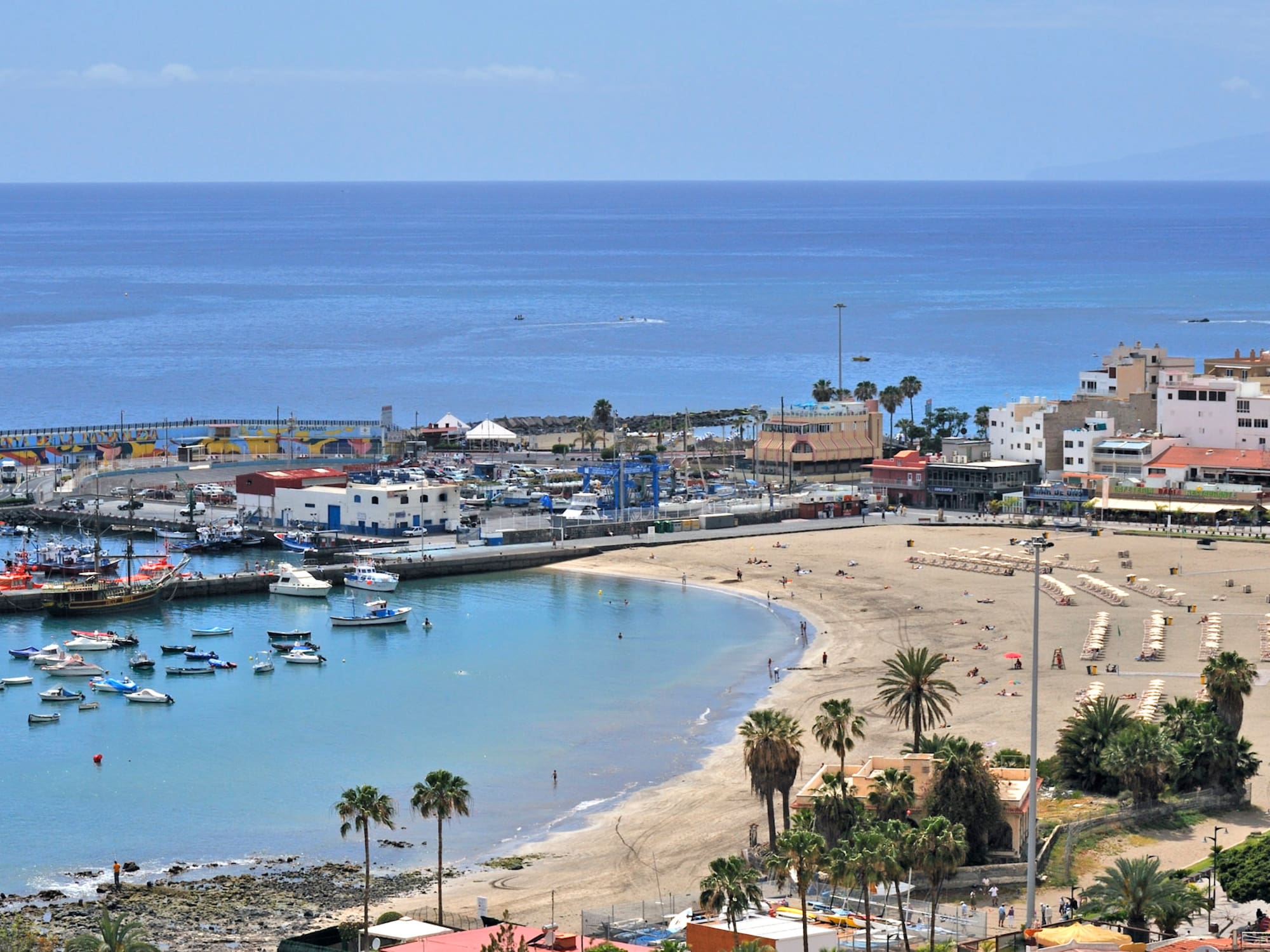 Aerial view of Los Cristianos Beach, harbor with boats, and coastal town.