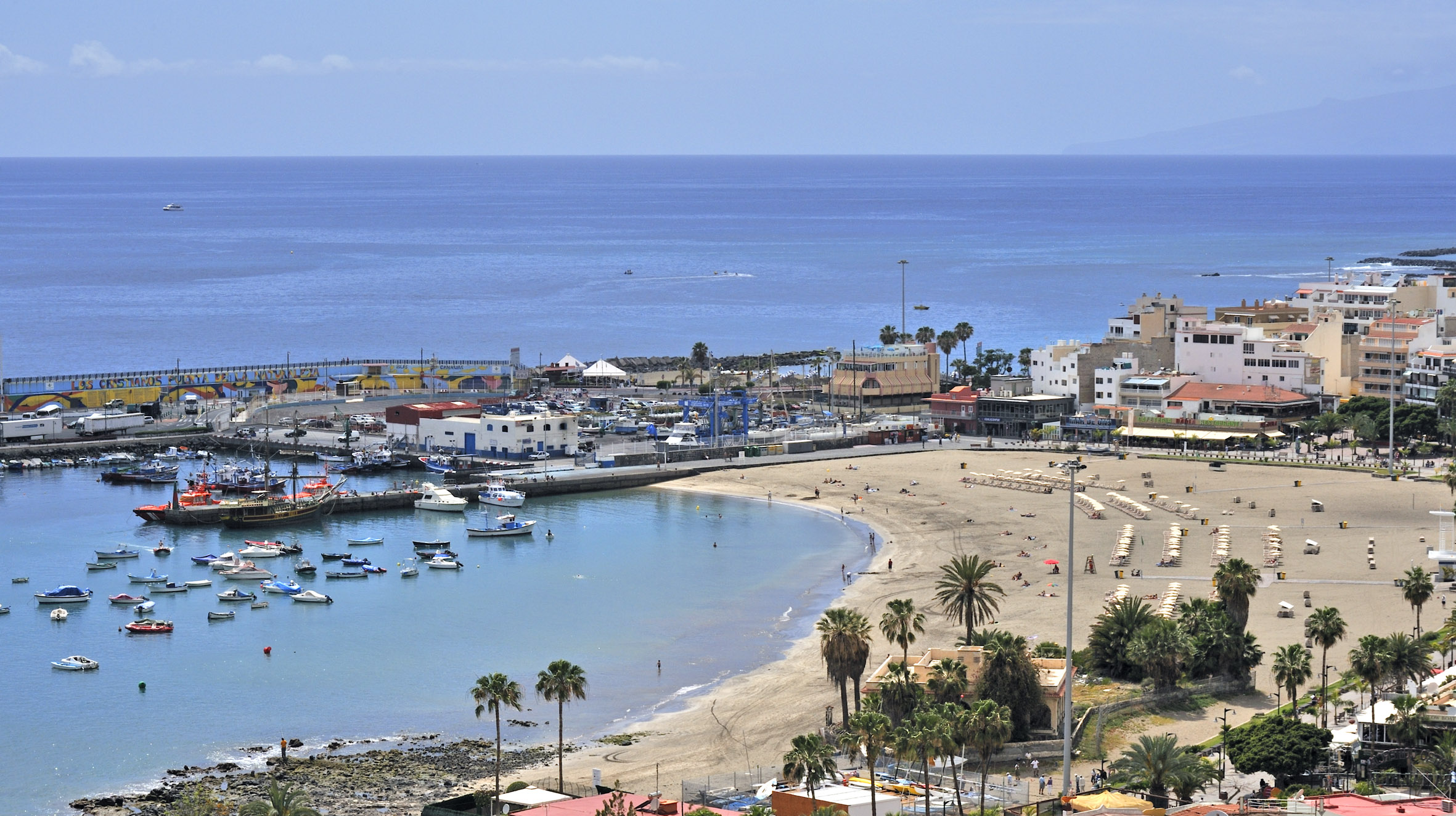 Aerial view of Los Cristianos Beach, harbor with boats, and coastal town.