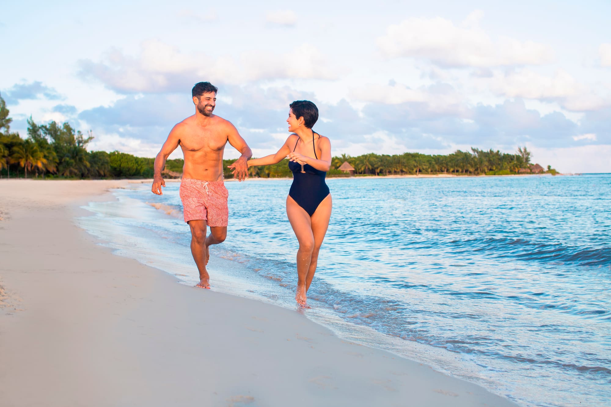 a man and woman running on a beach