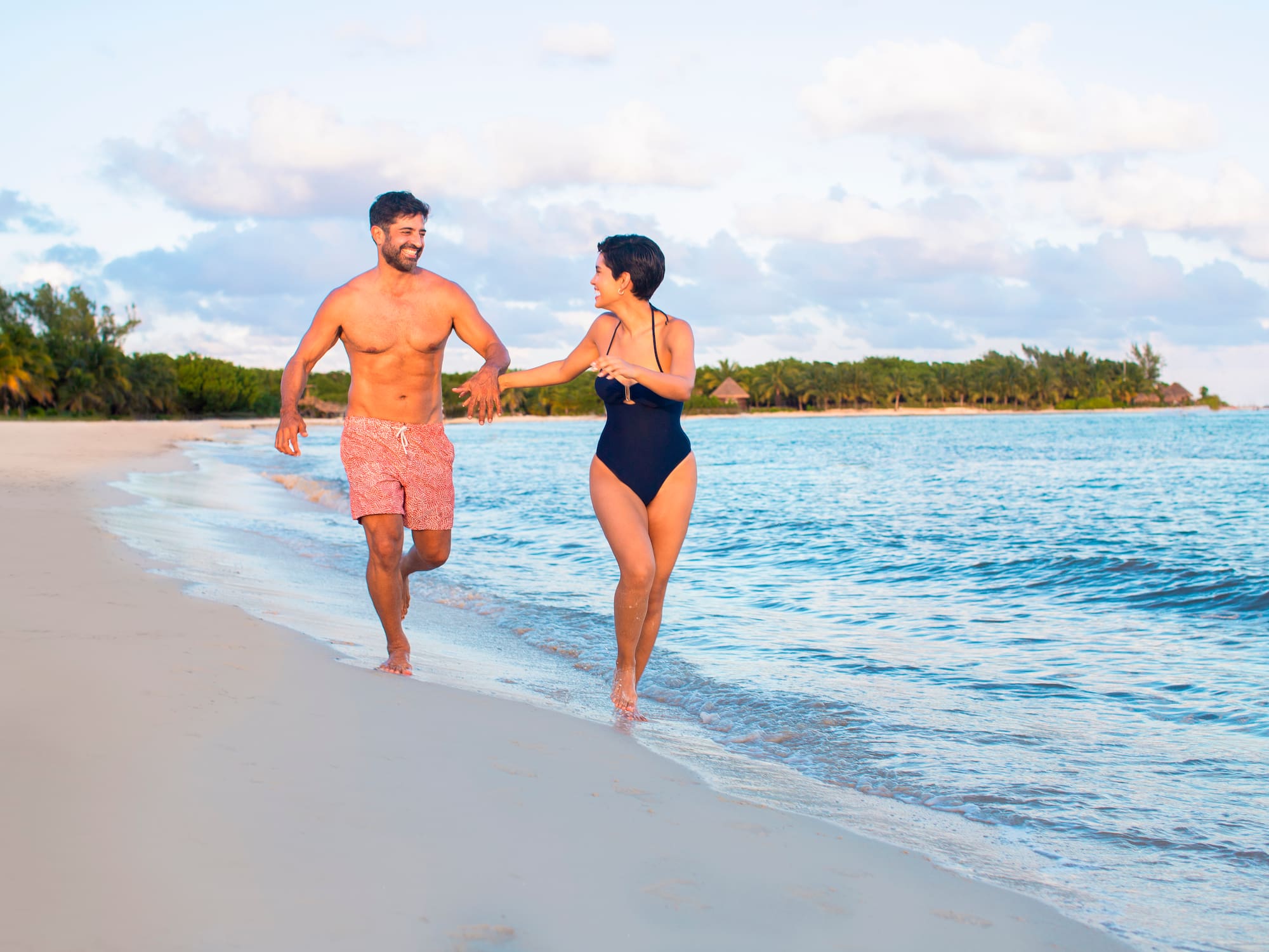 a man and woman running on a beach