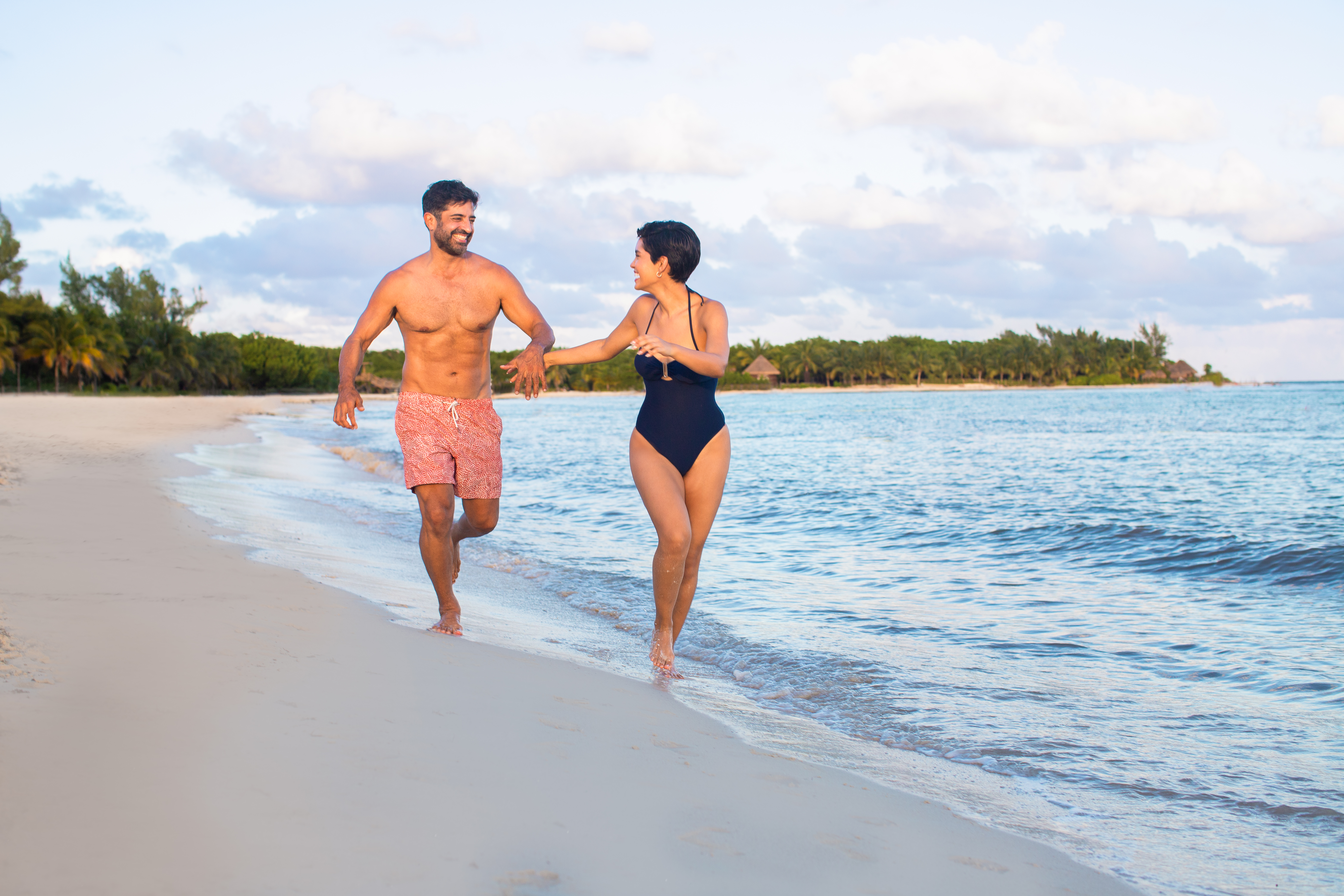 a man and woman running on a beach