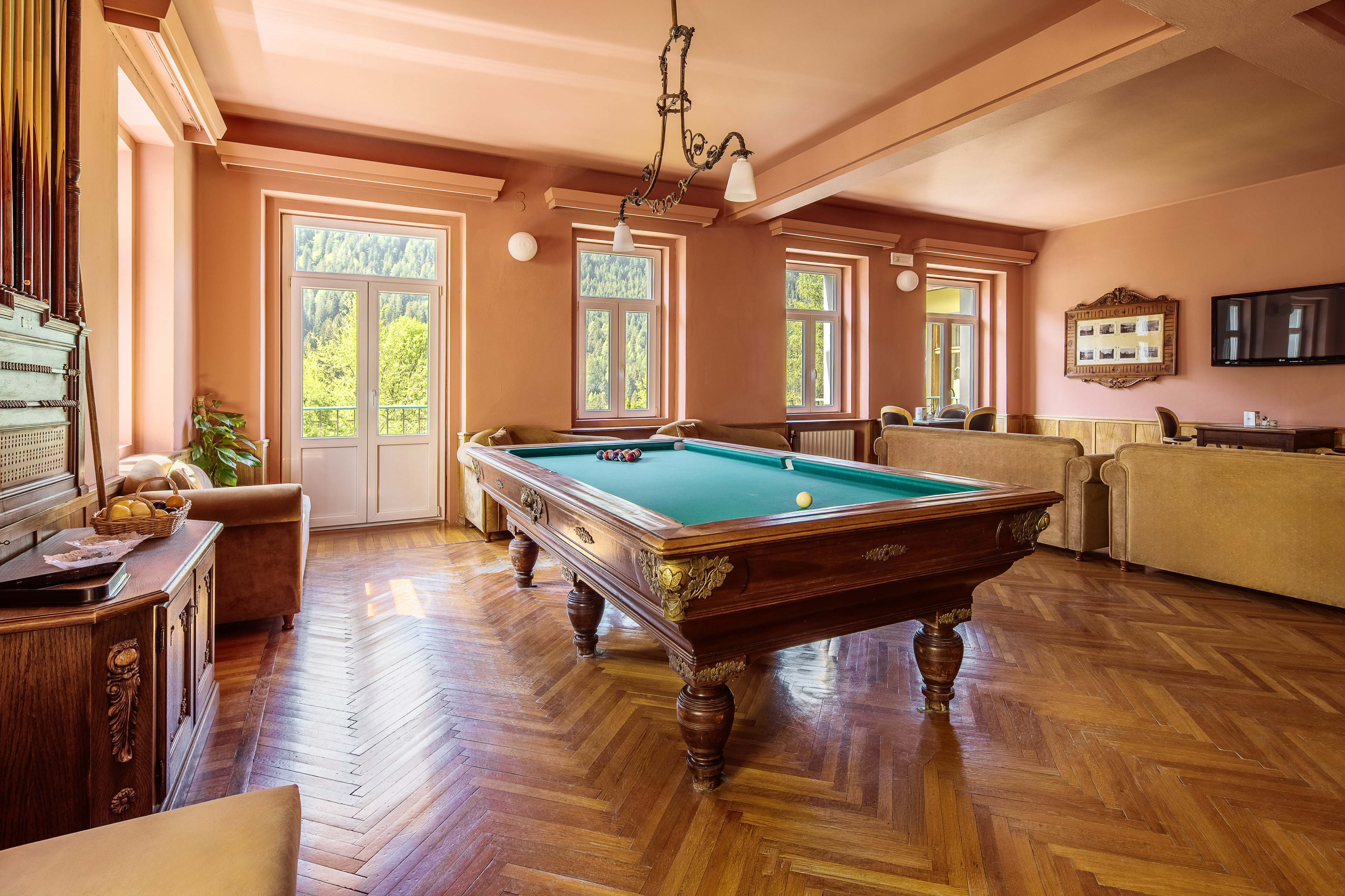 Vintage game room with pool table, parquet floor, and scenic mountain views.