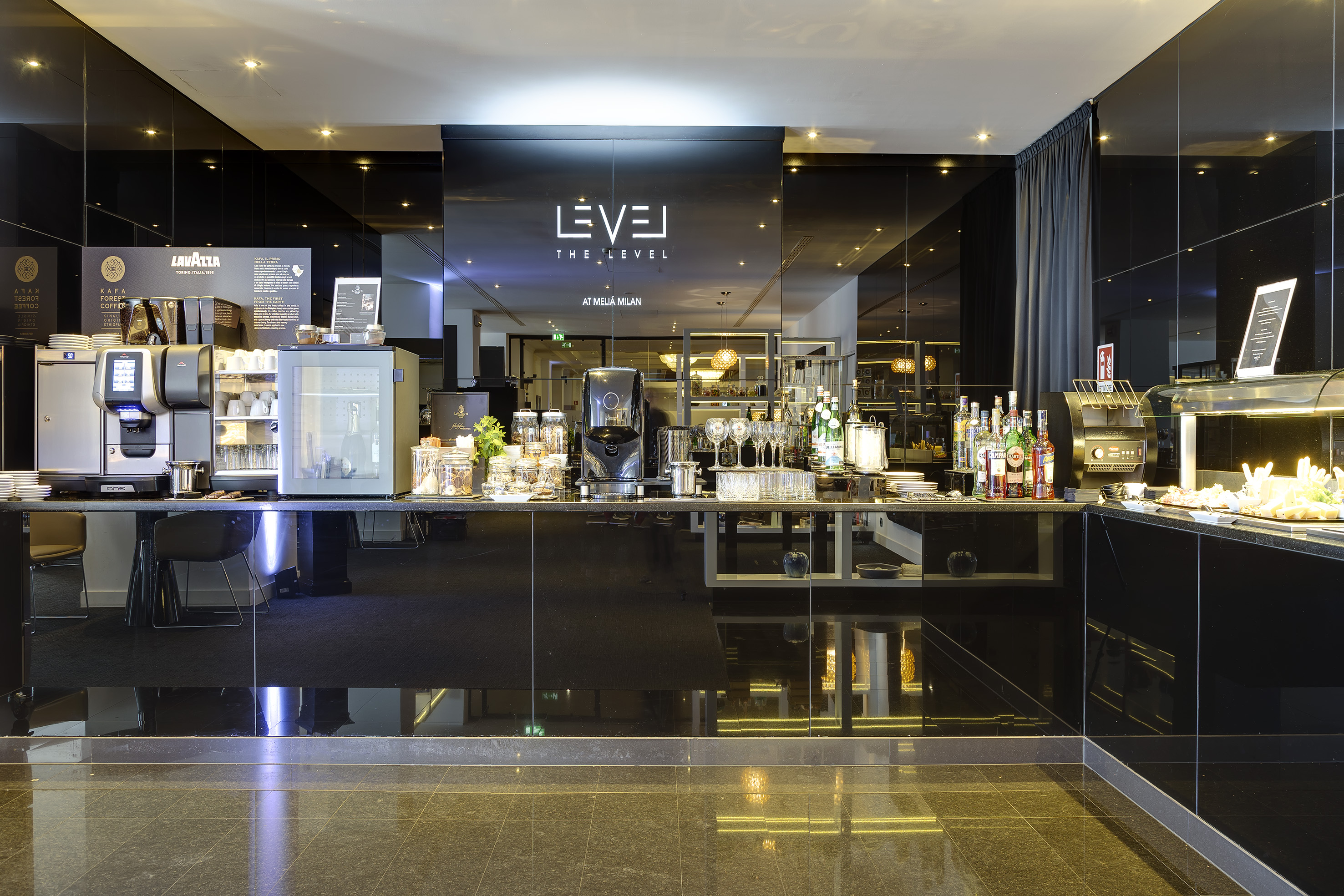 Melia Milan The Level hotel lounge with coffee bar and breakfast buffet.