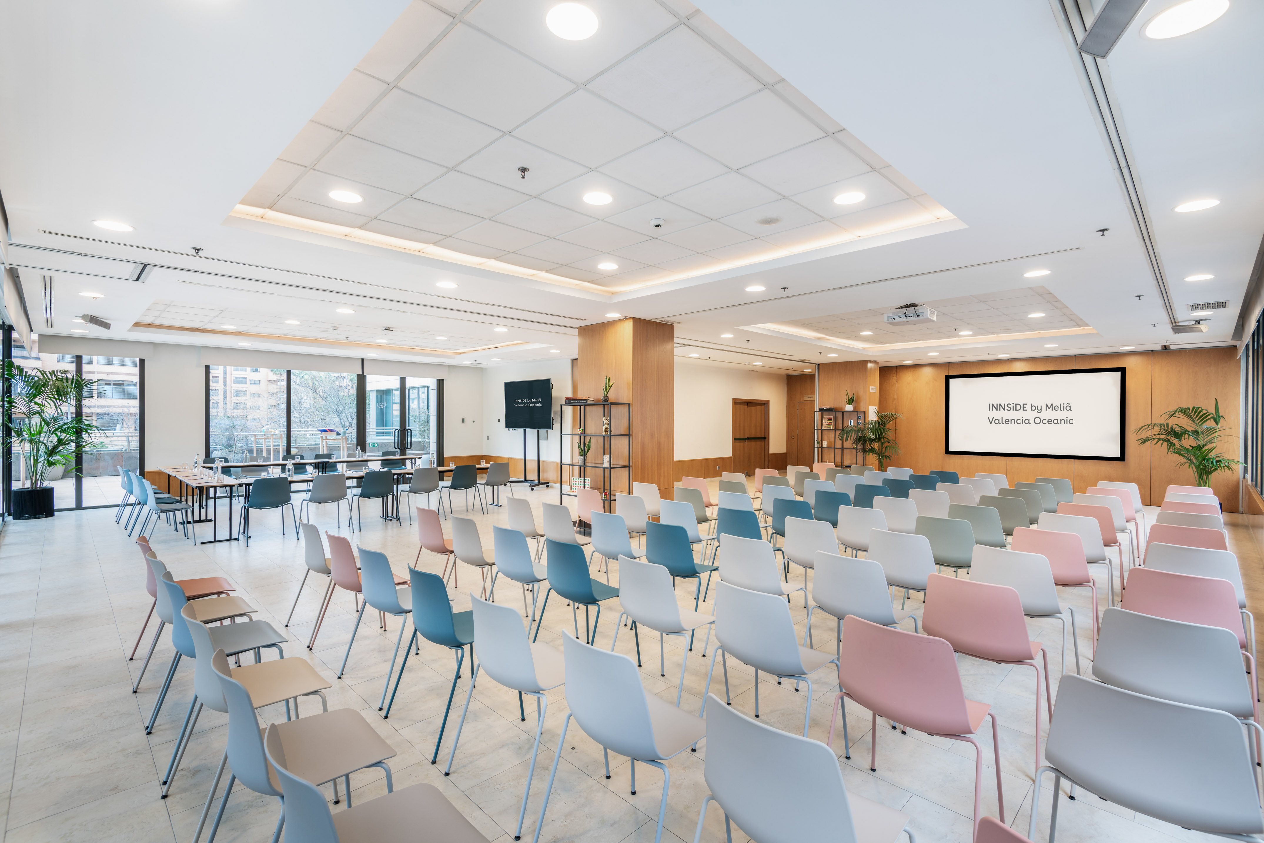 Modern hotel conference room with colorful chairs, presentation screen.