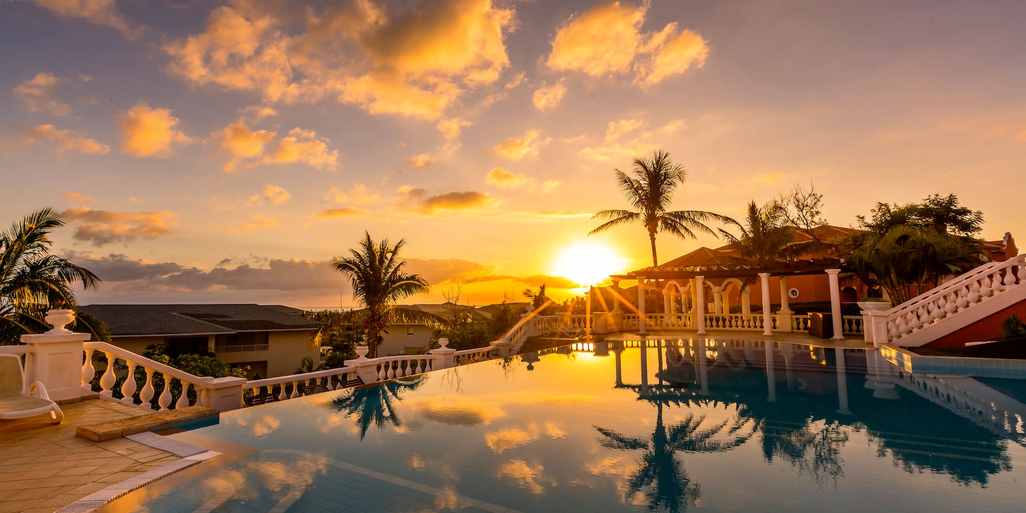 a pool with palm trees and a sunset