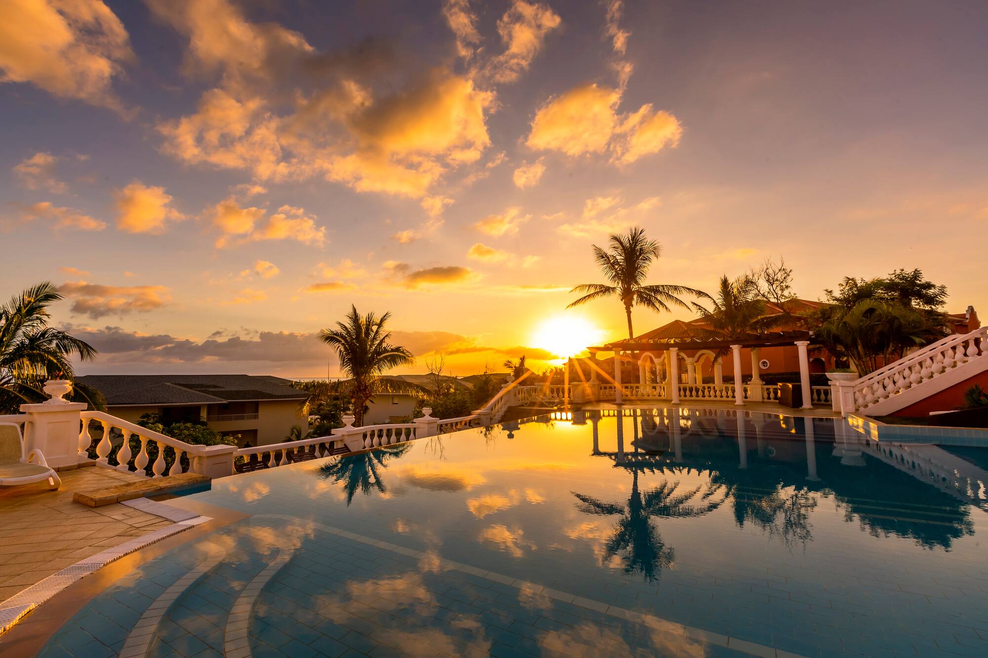 a pool with palm trees and a sunset