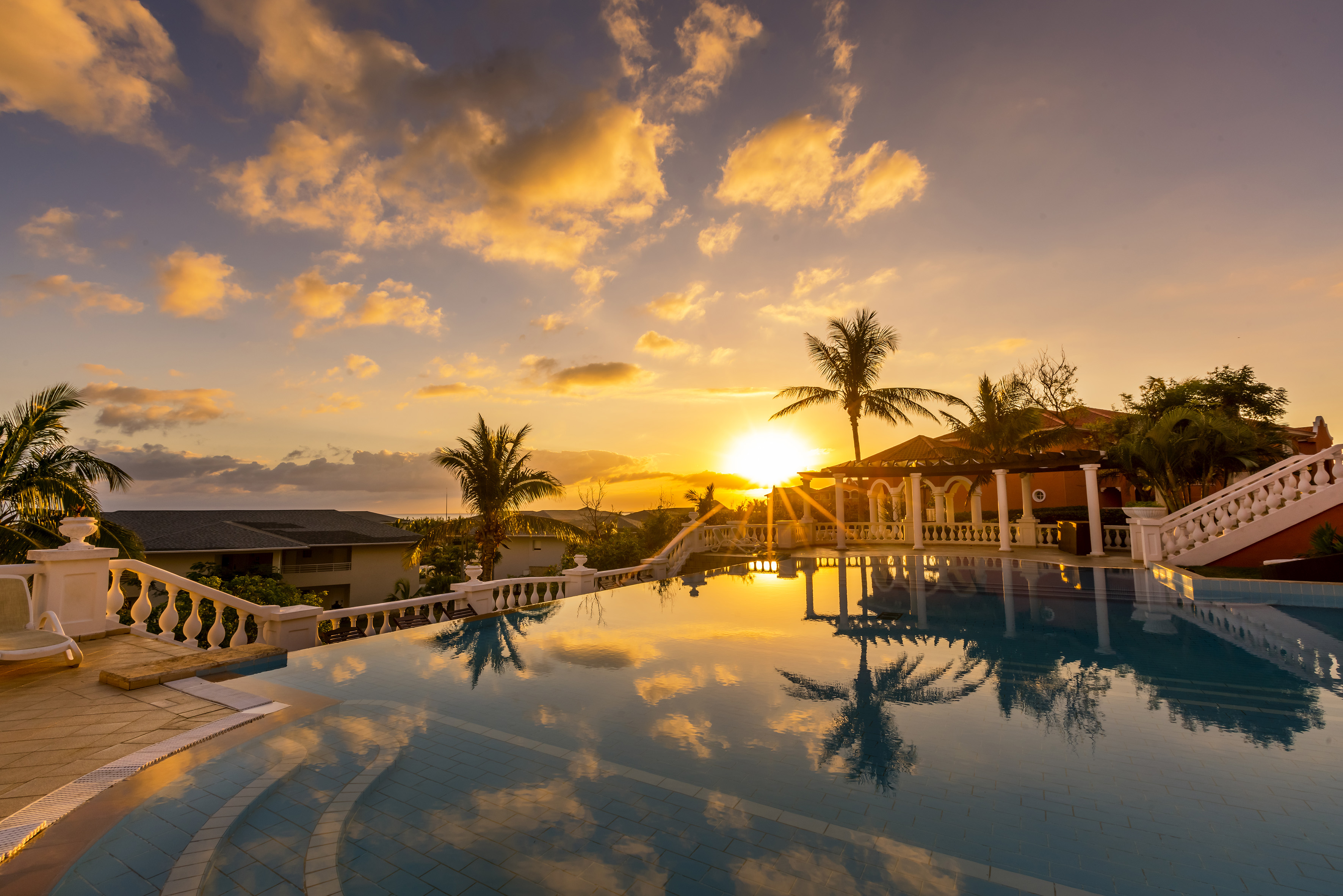 a pool with palm trees and a sunset