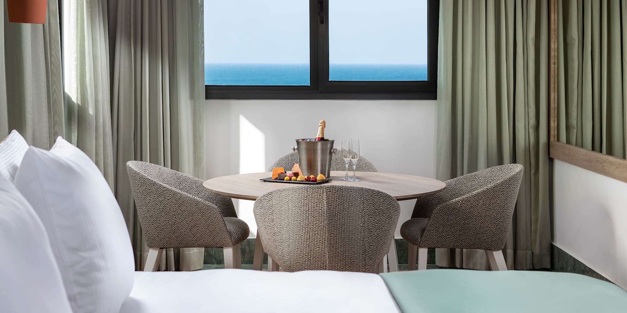 a table with a bucket of champagne and chairs in a hotel room