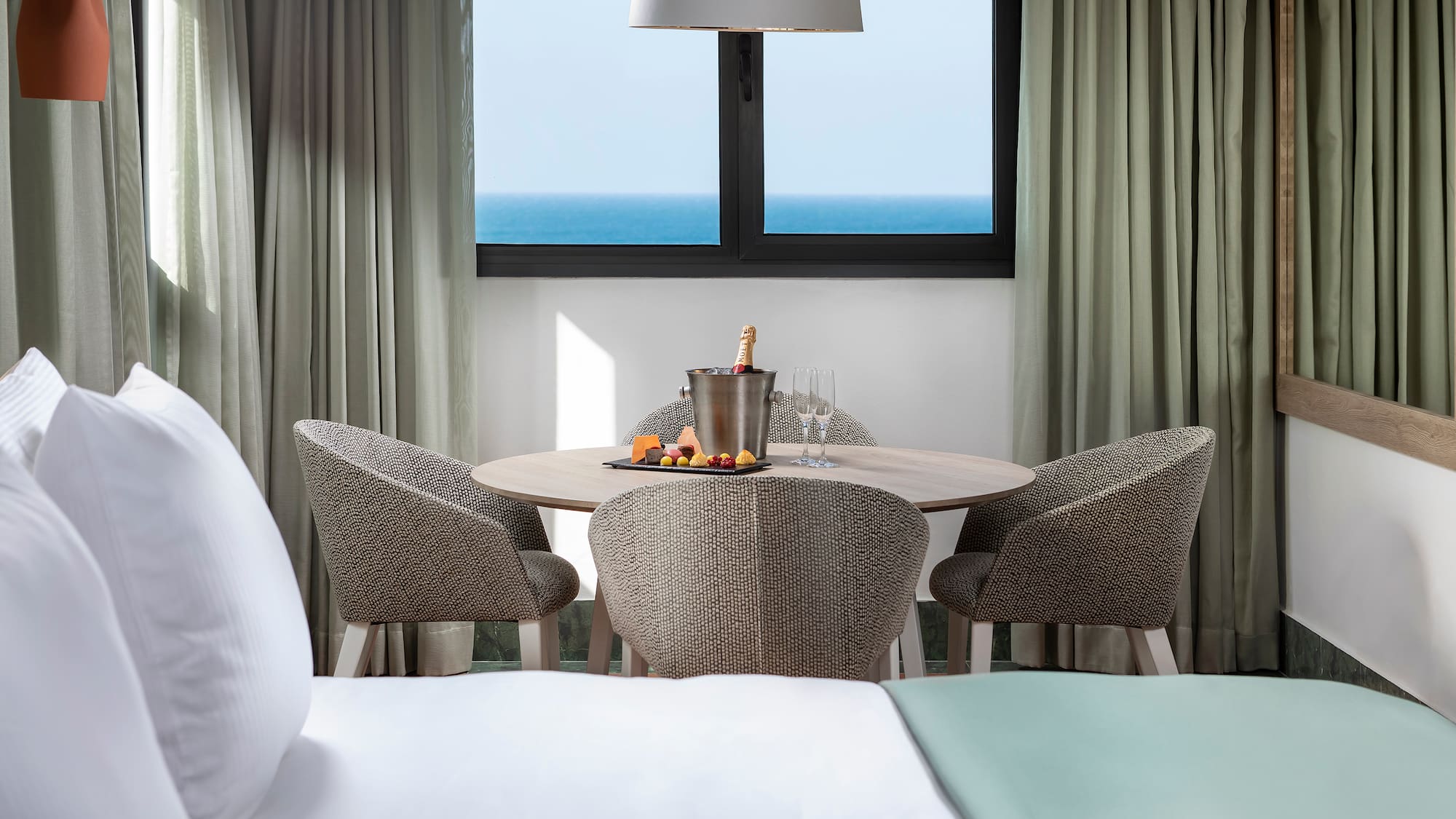 a table with a bucket of champagne and chairs in a hotel room