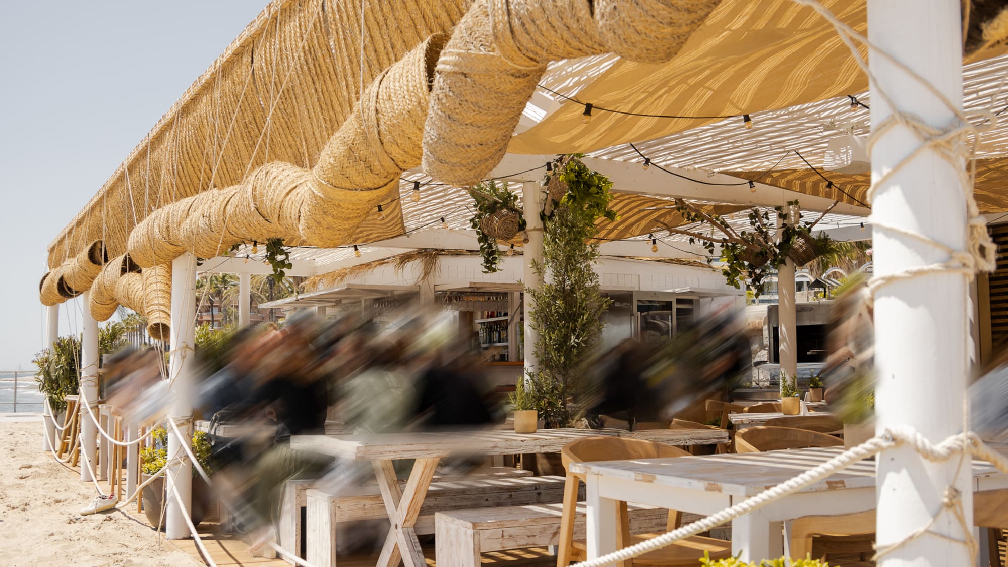 a beach covered area with a wooden deck and tables and chairs