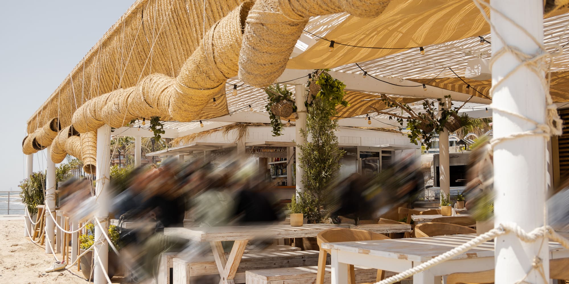 a beach covered area with a wooden deck and tables and chairs
