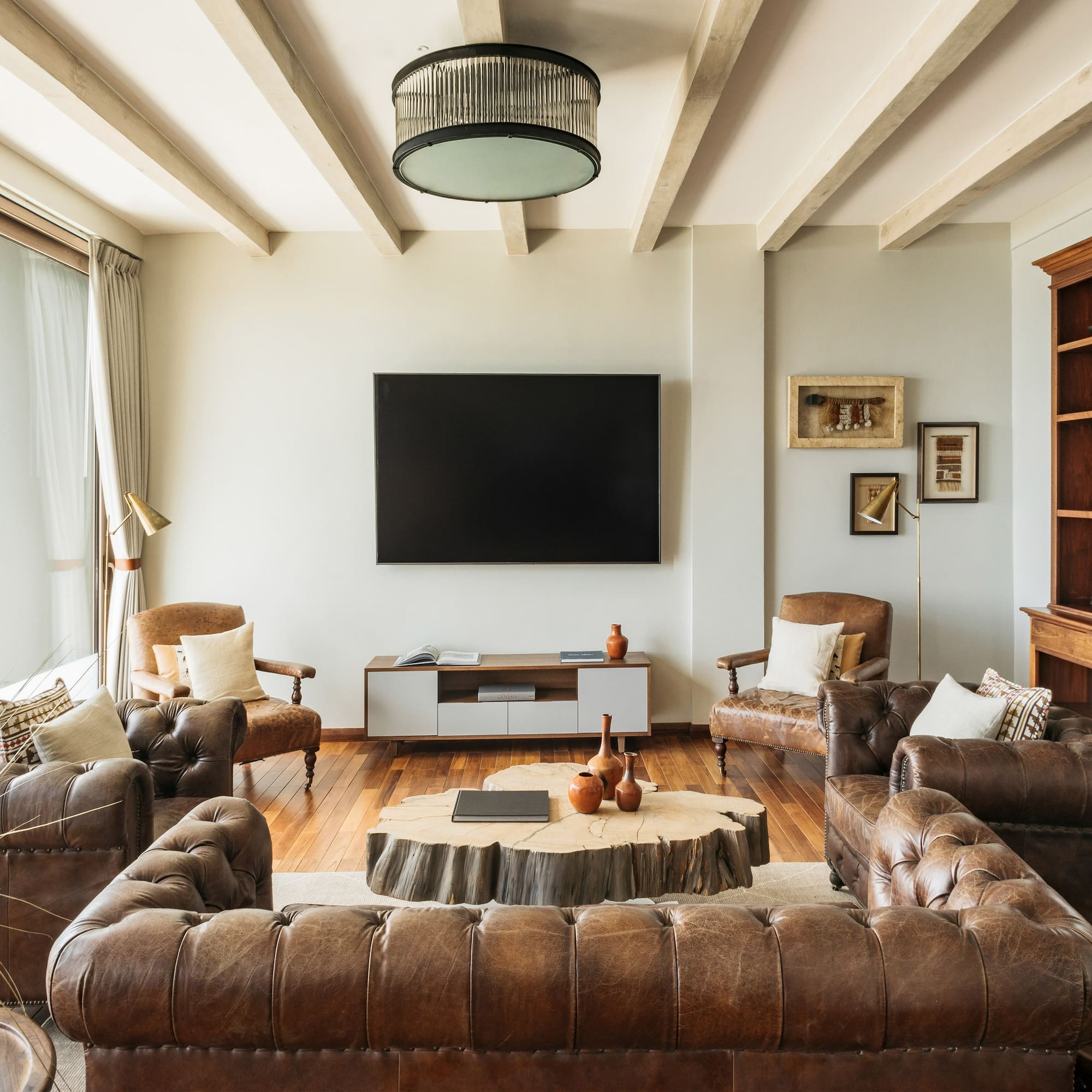 Rustic modern living room, brown leather sofas, wood coffee table, balcony view.